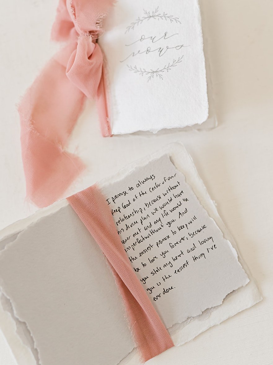 Homemade vow books with pink ribbon for an elegant summer wedding.