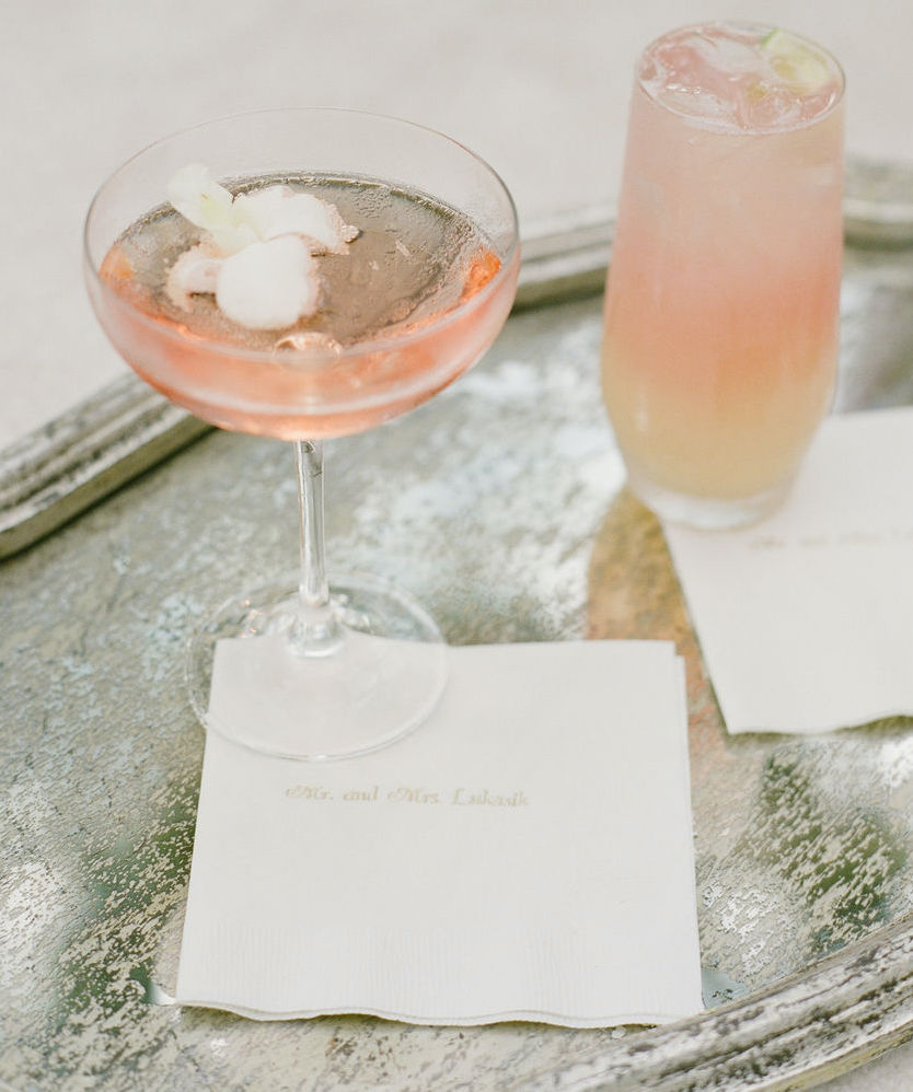 A coupe champagne glass with a peach cocktail in it on a silver tray.