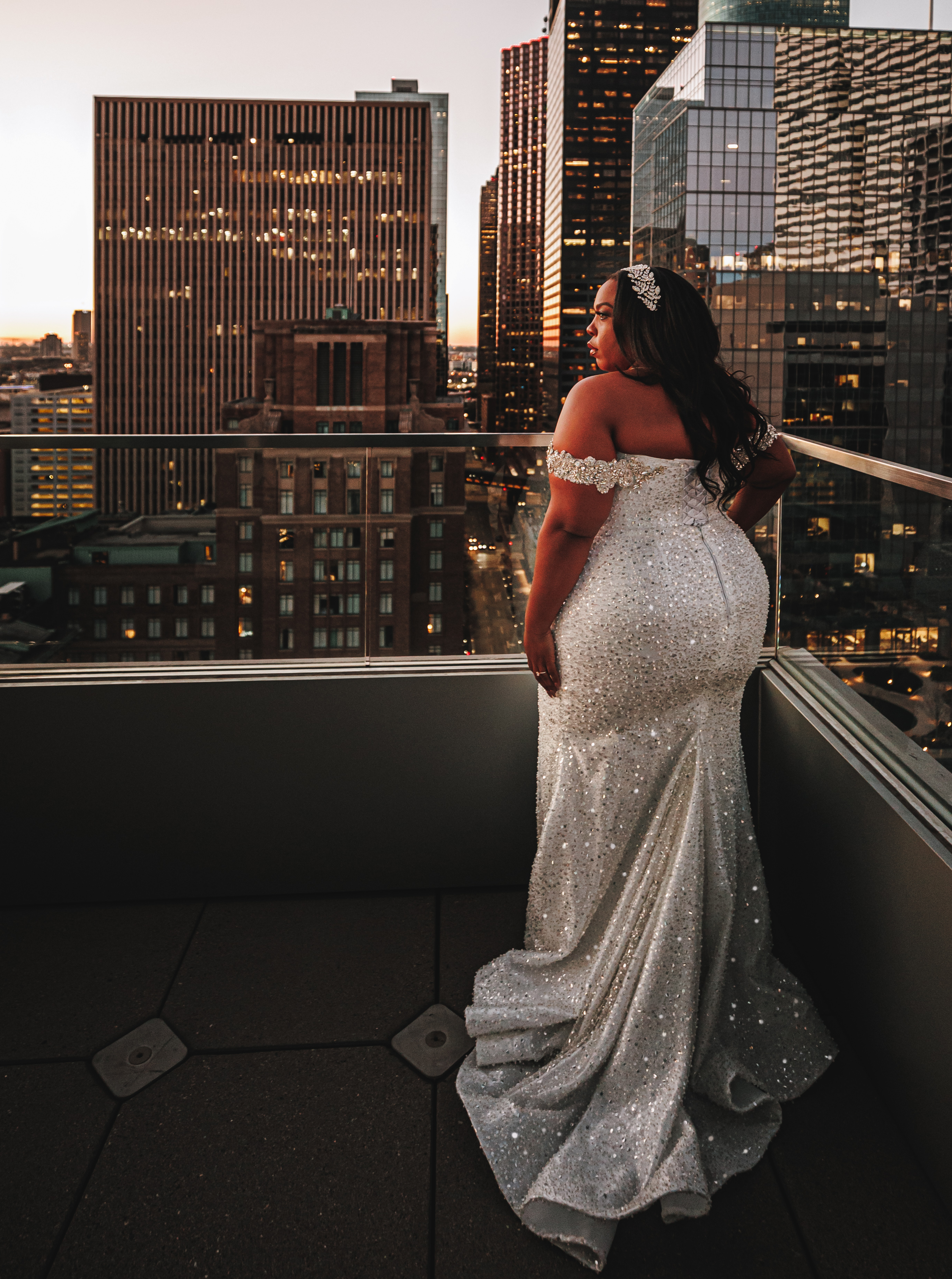 Ashley Turner is wearing her wedding gown while on a balcony overlooking the Houston skyline during her bridal shoot at sunset.