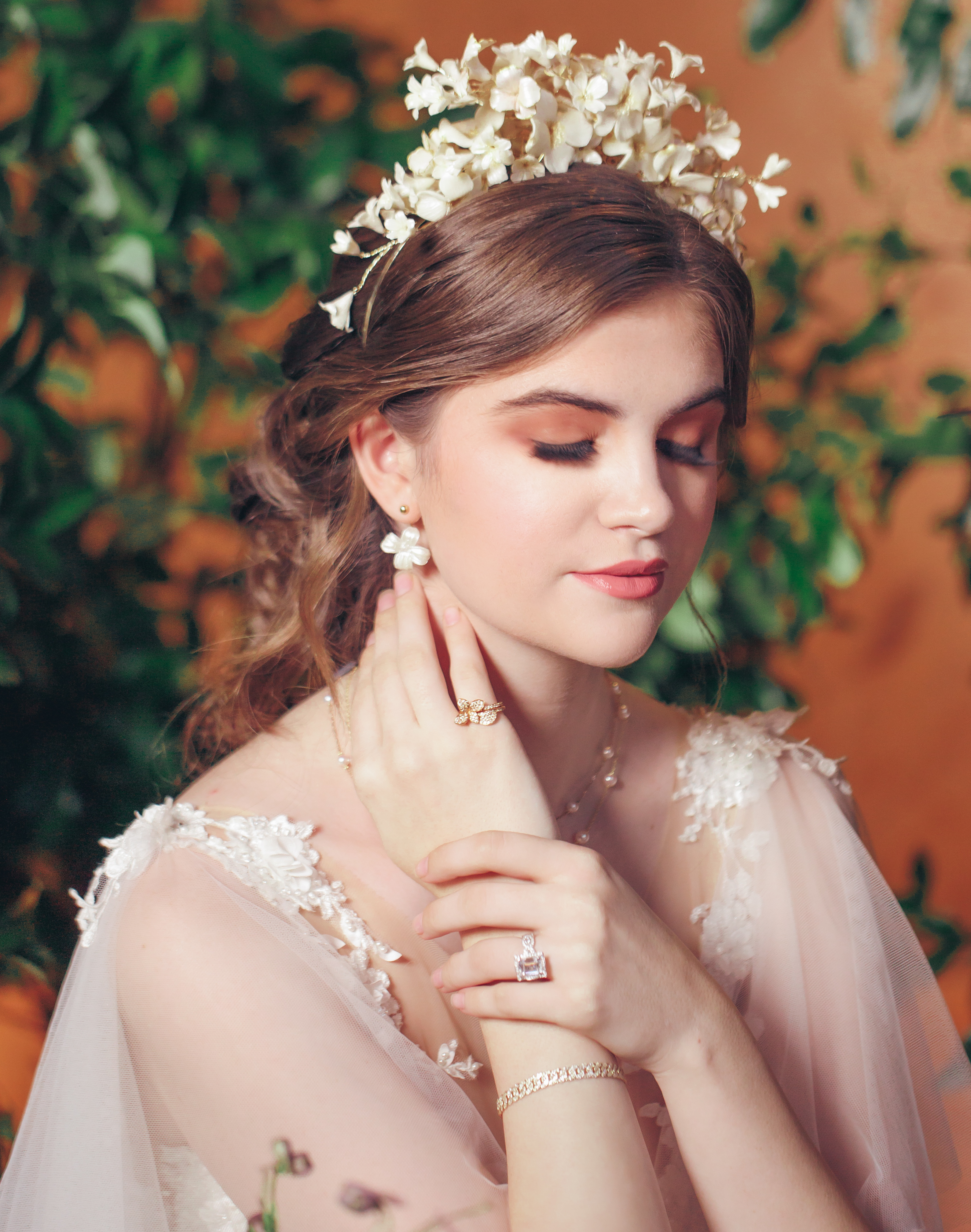 An up close photo of a bride closing her eyes and wearing a floral headpiece and luxury jewelry.