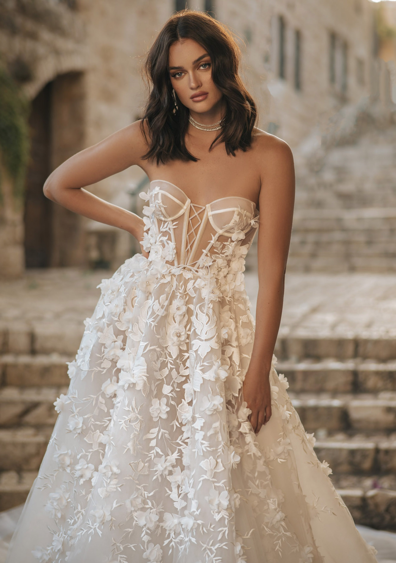 A bride wears a Berta gown that has a flowy skirt with 3D embellished flowers stitched onto it.