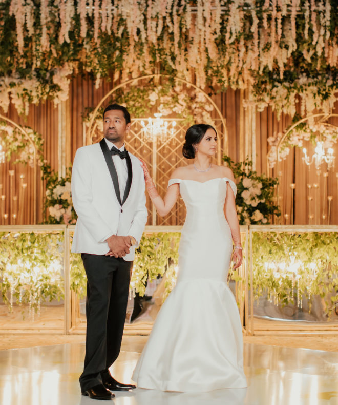 south asian groom and bride pose inside of ballroom at san luis resort, spa and conference center on their wedding day. 