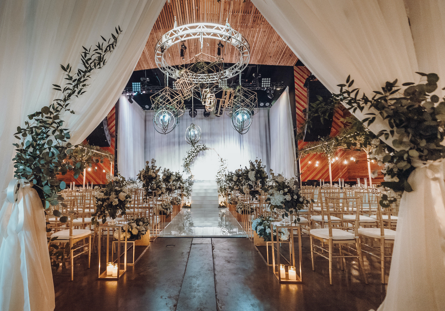 An elegant wedding ceremony decorated with cream flowers and greenery is set up in a music venue in Houston, TX.