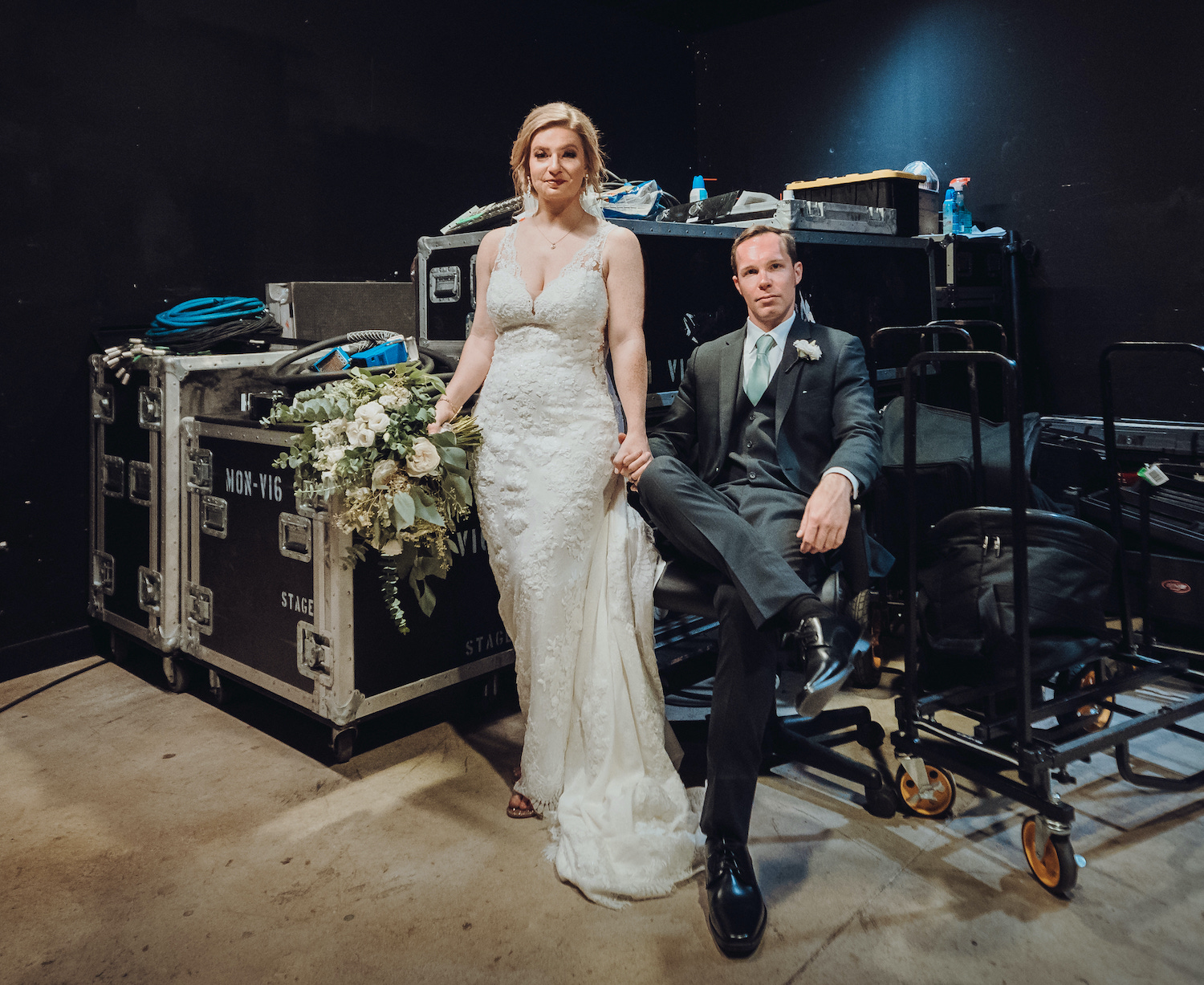 A bride and groom pose in front of musical equipment at their concert style venue.