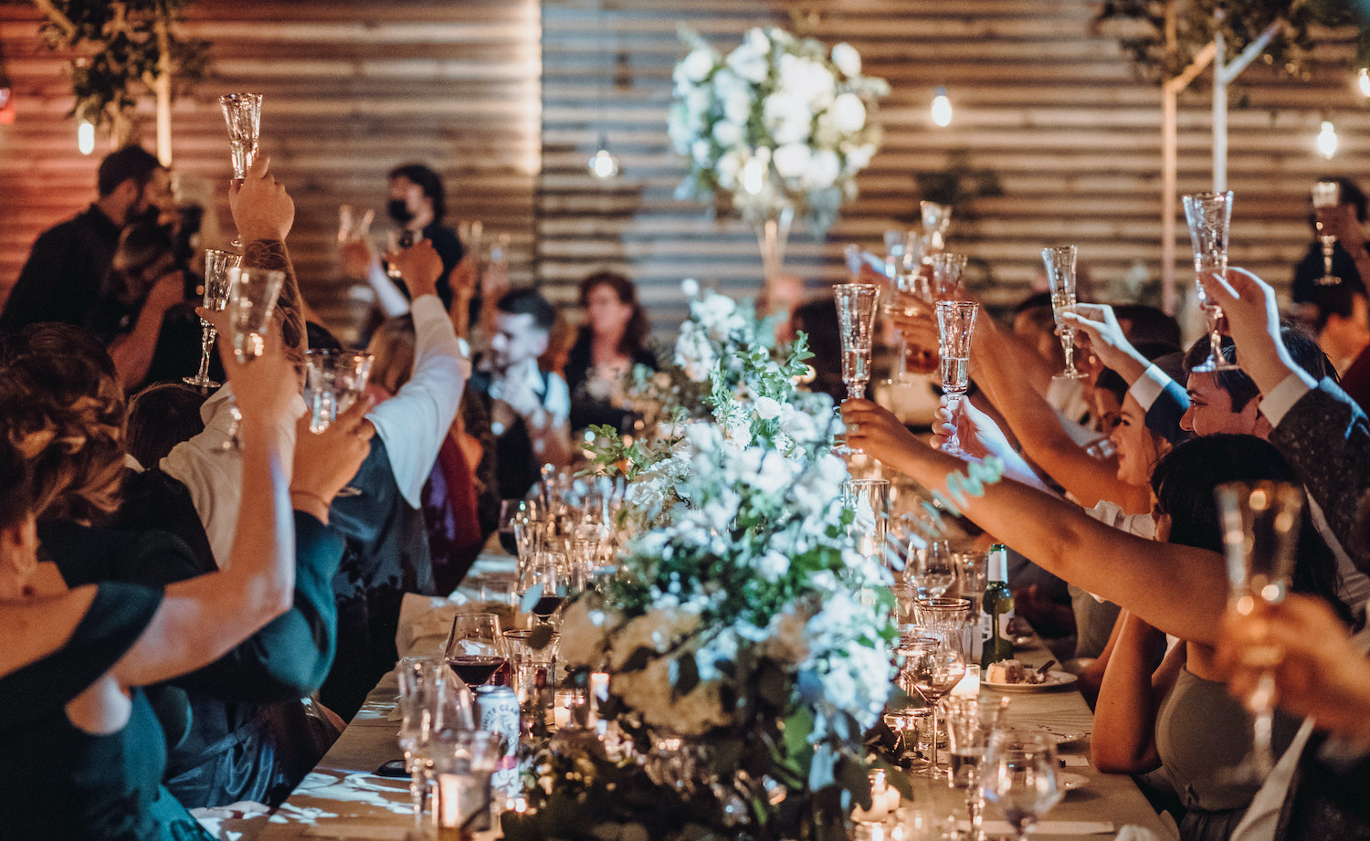 Wedding guests hold their champagne glasses in the air for a toast for the newlyweds at a venue in Houston, TX.