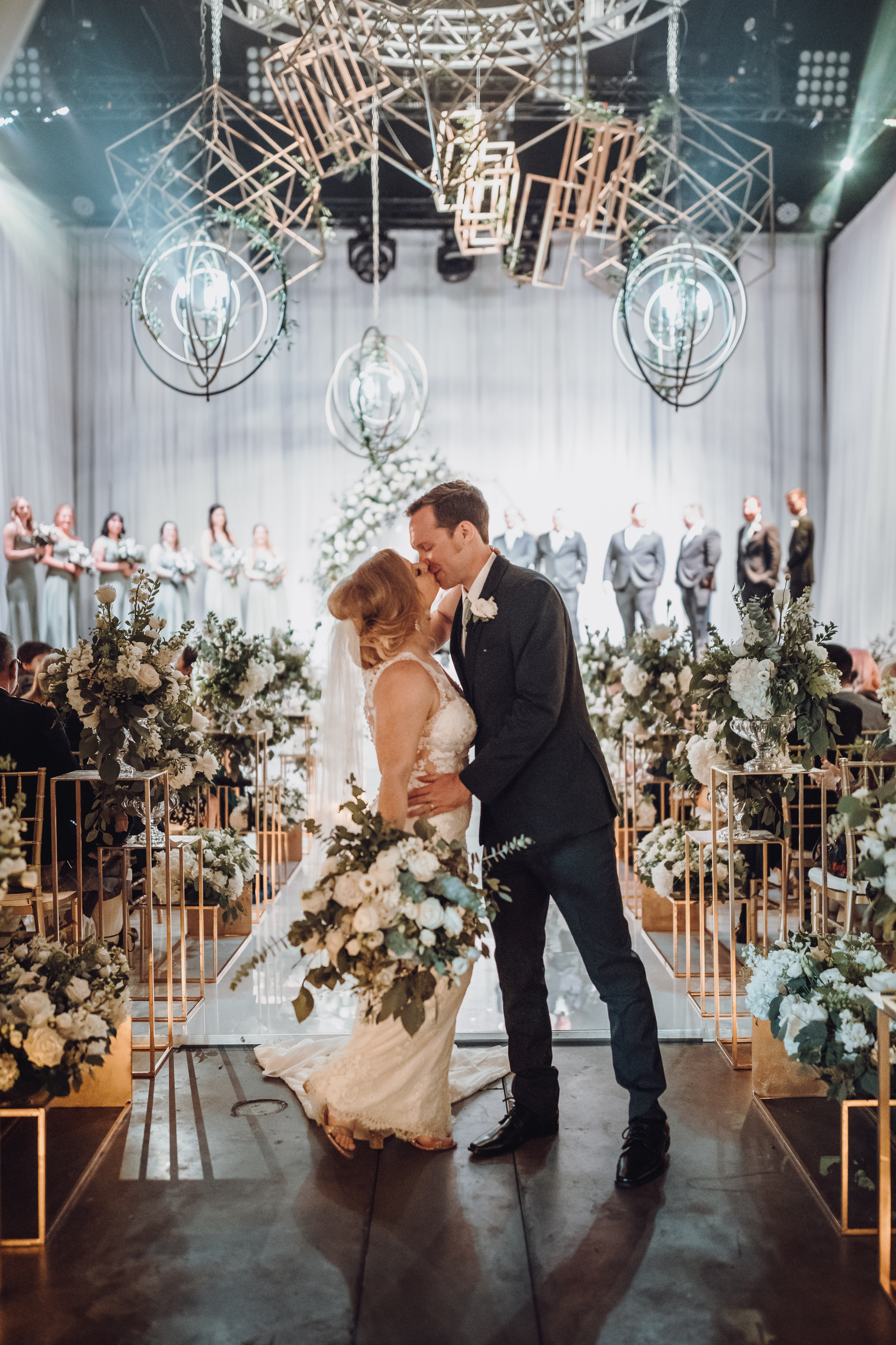 A bride and groom kiss in the aisle at their wedding ceremony in Houston, TX.