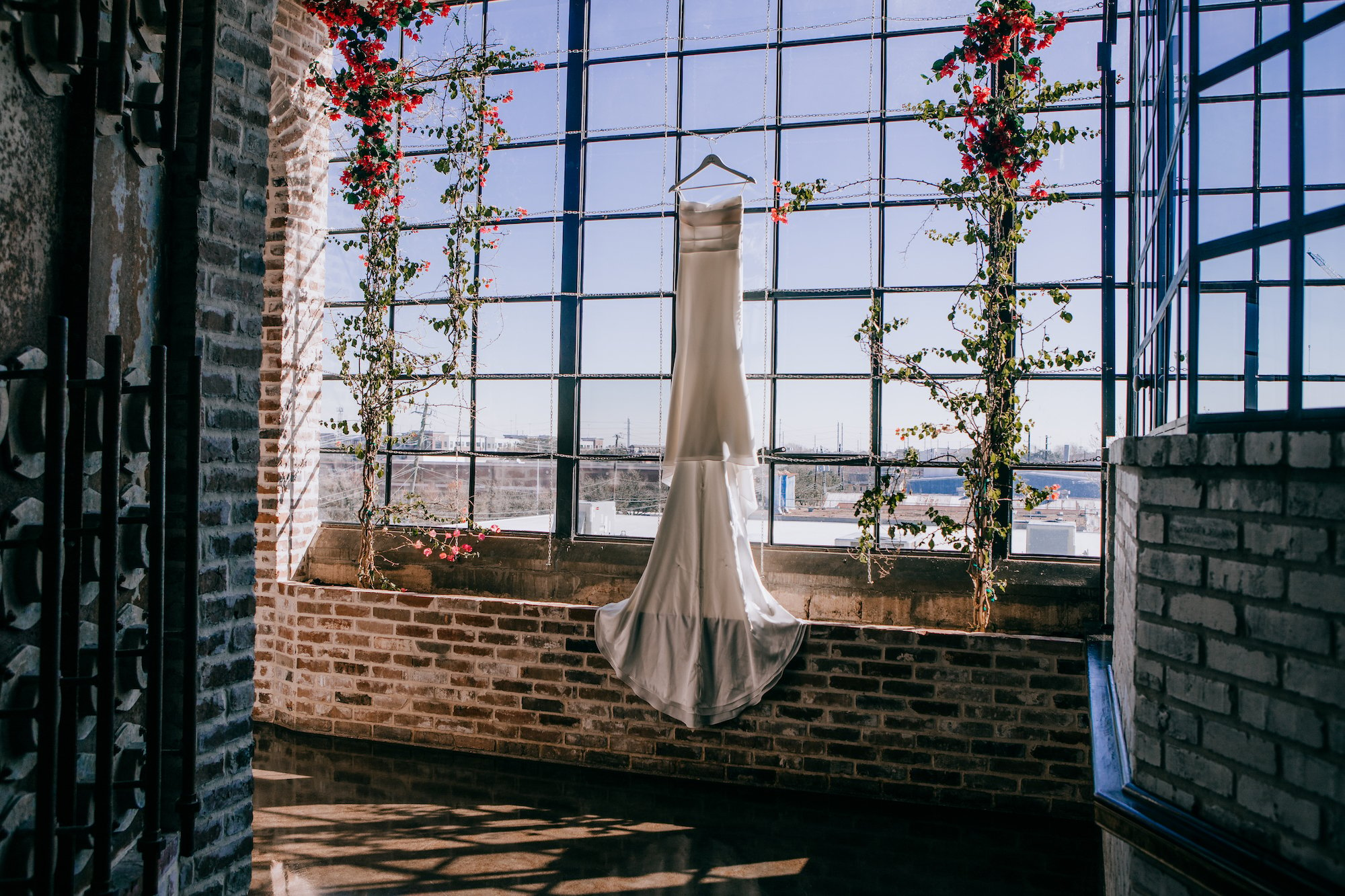 A wedding gown hangs in front of a window at a wedding venue in Houston.