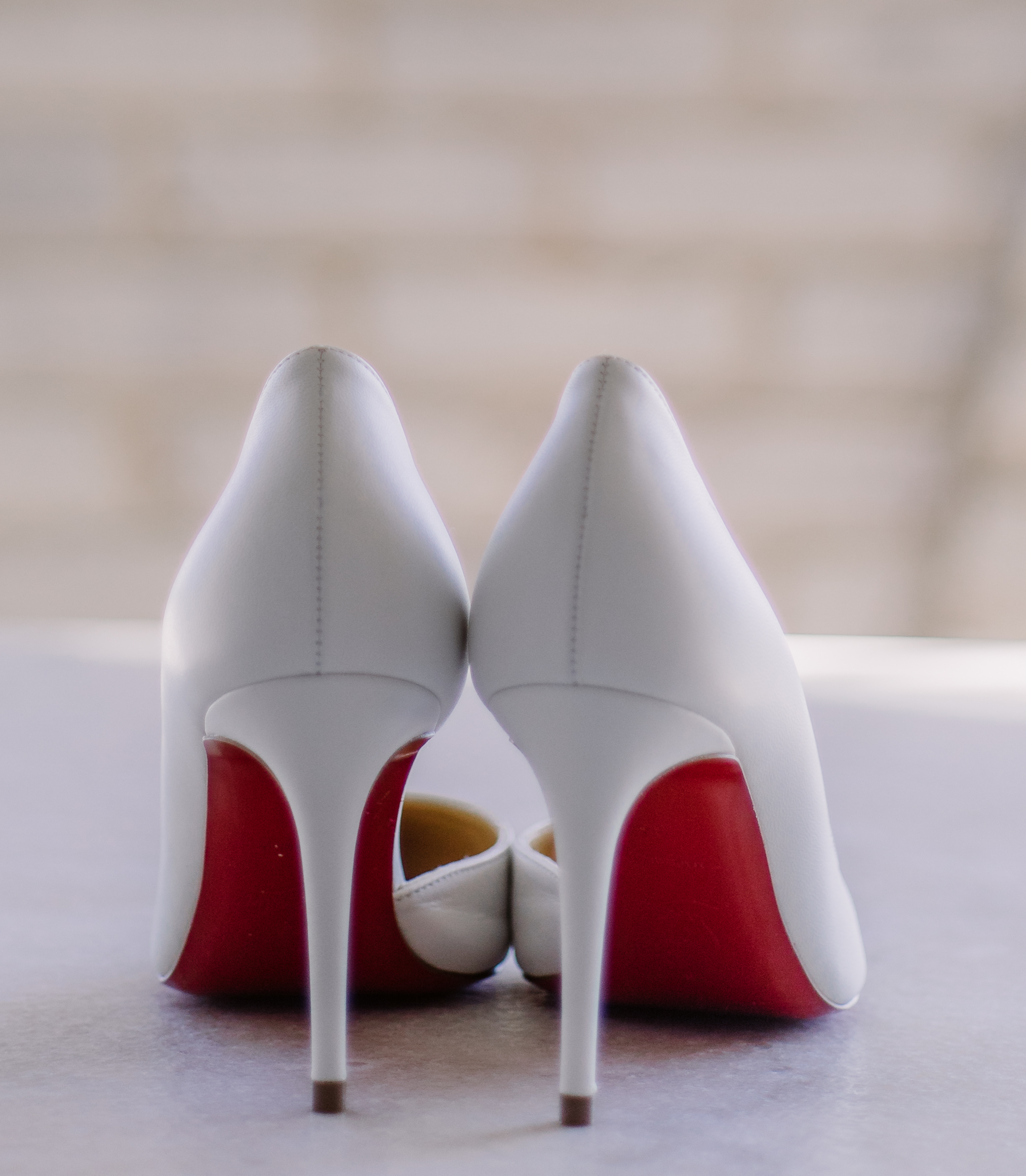 A bride's Louboutin shoes are placed on a table before her wedding in Houston, TX.