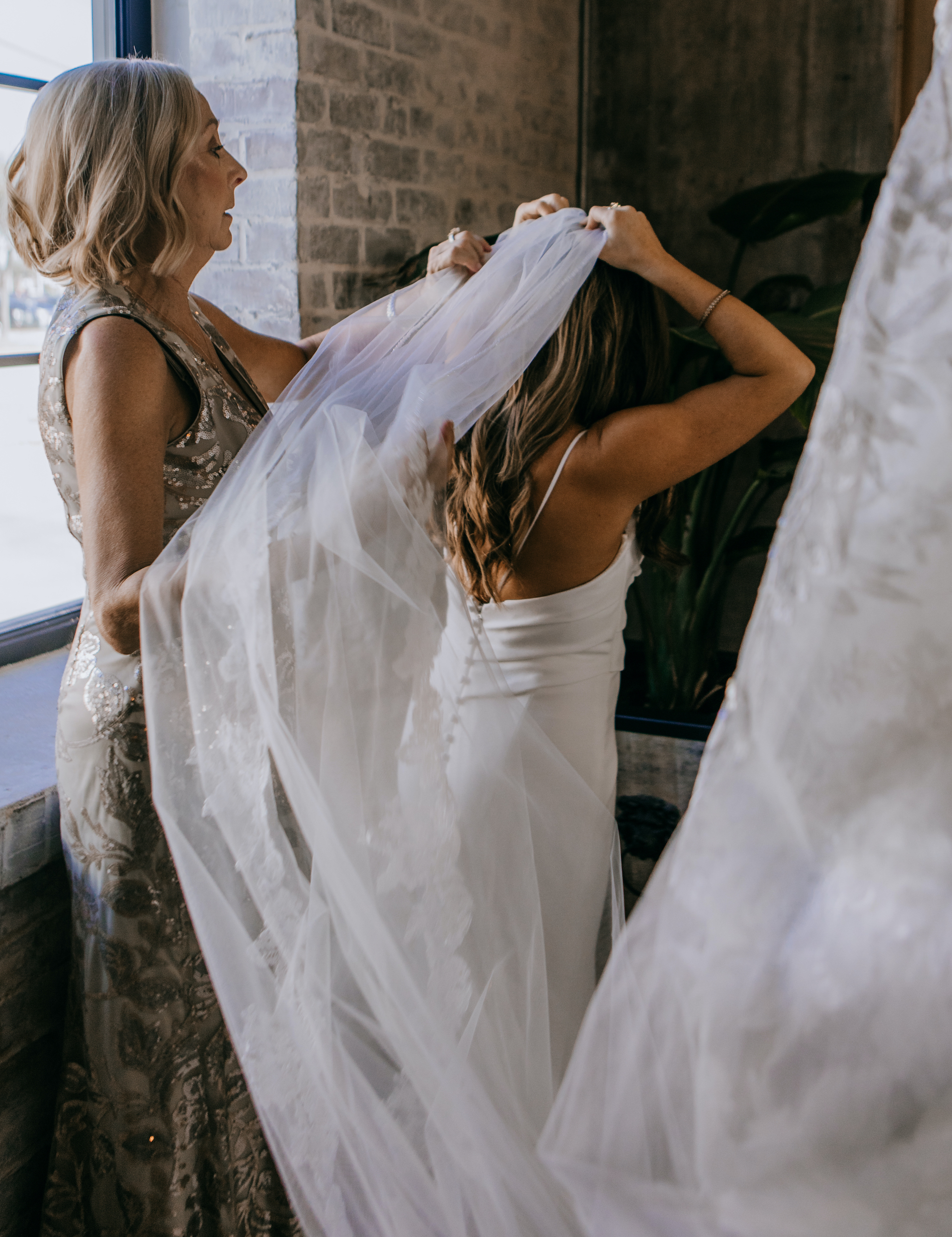 A bride's mom helps her put on her veil before her wedding at a venue in Houston, TX.