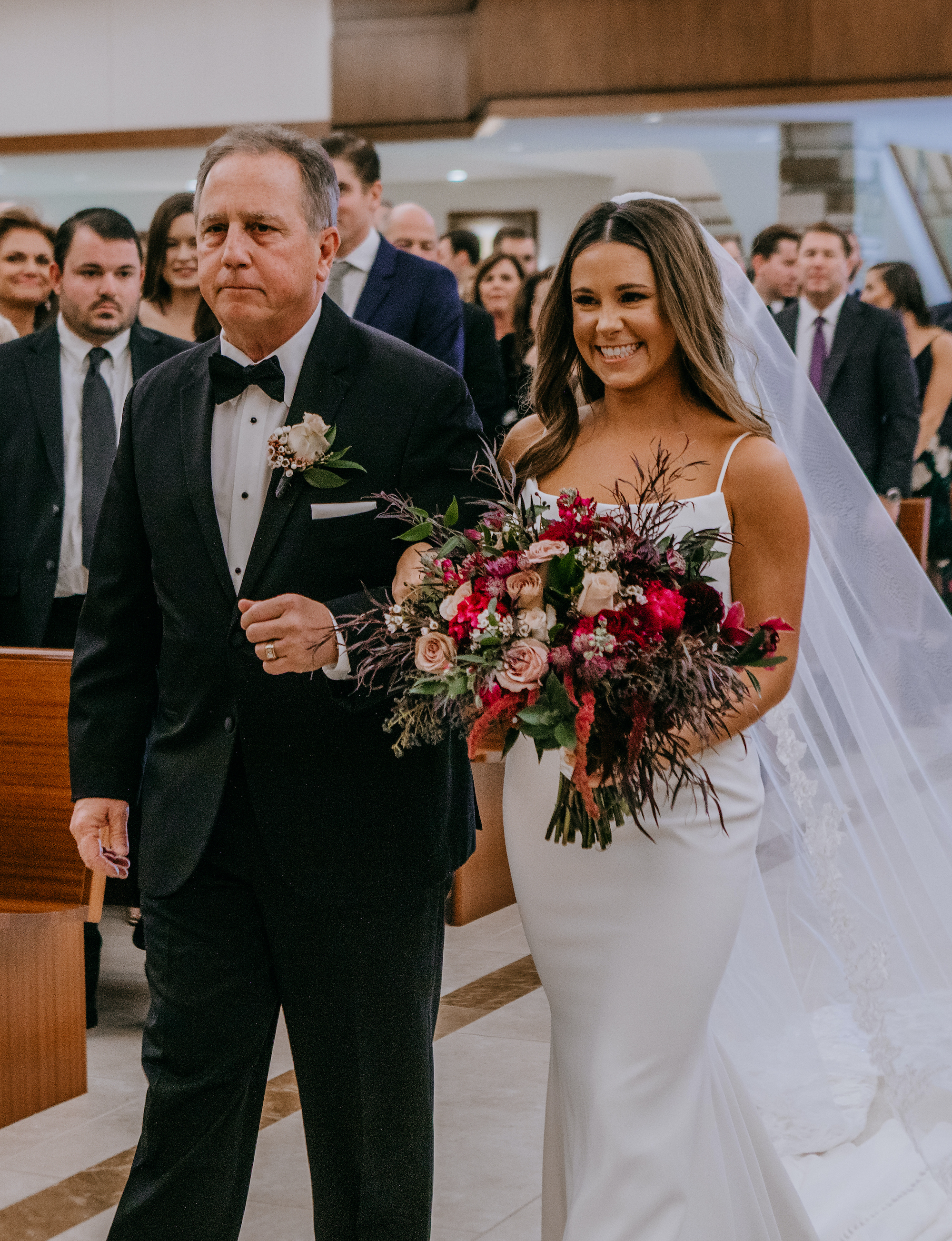 A bride walks down the aisle with her dad at her wedding ceremony in Houston, TX.