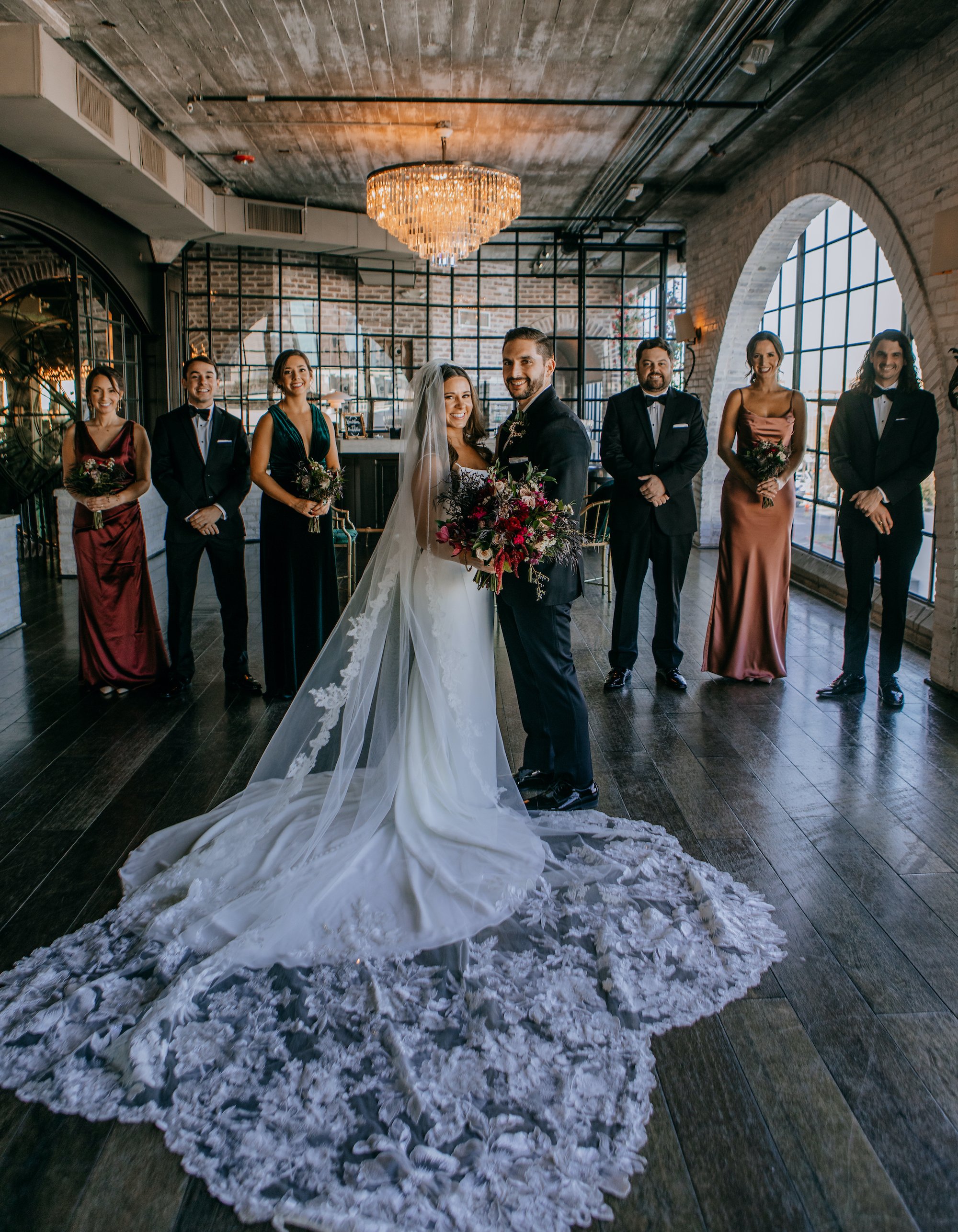 A bride and groom stand with their wedding party before their Jewel Toned Wedding With Art Deco Vibes