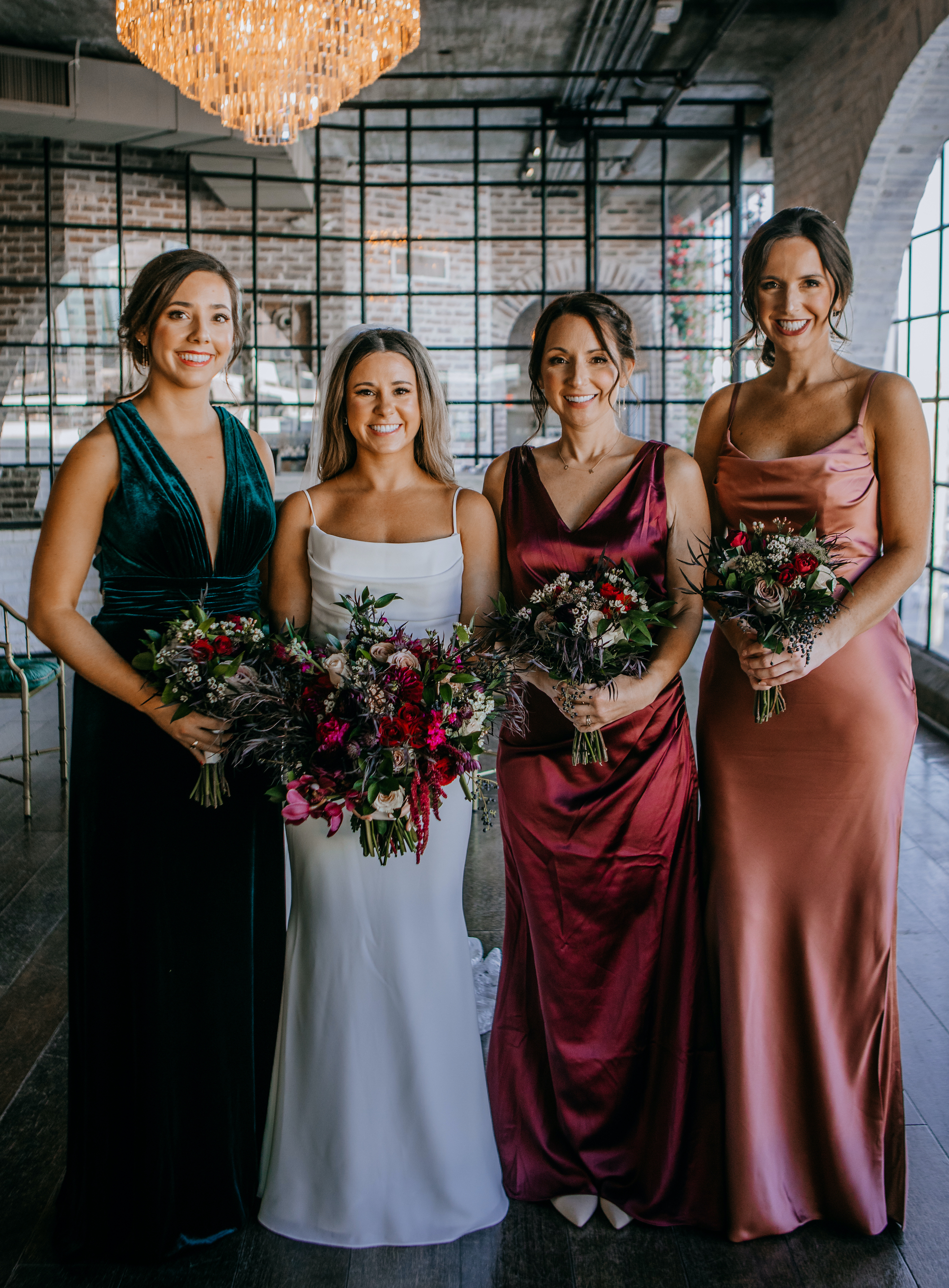 A bride stands with her bridesmaids before her reception for her Jewel Toned Wedding With Art Deco Vibes