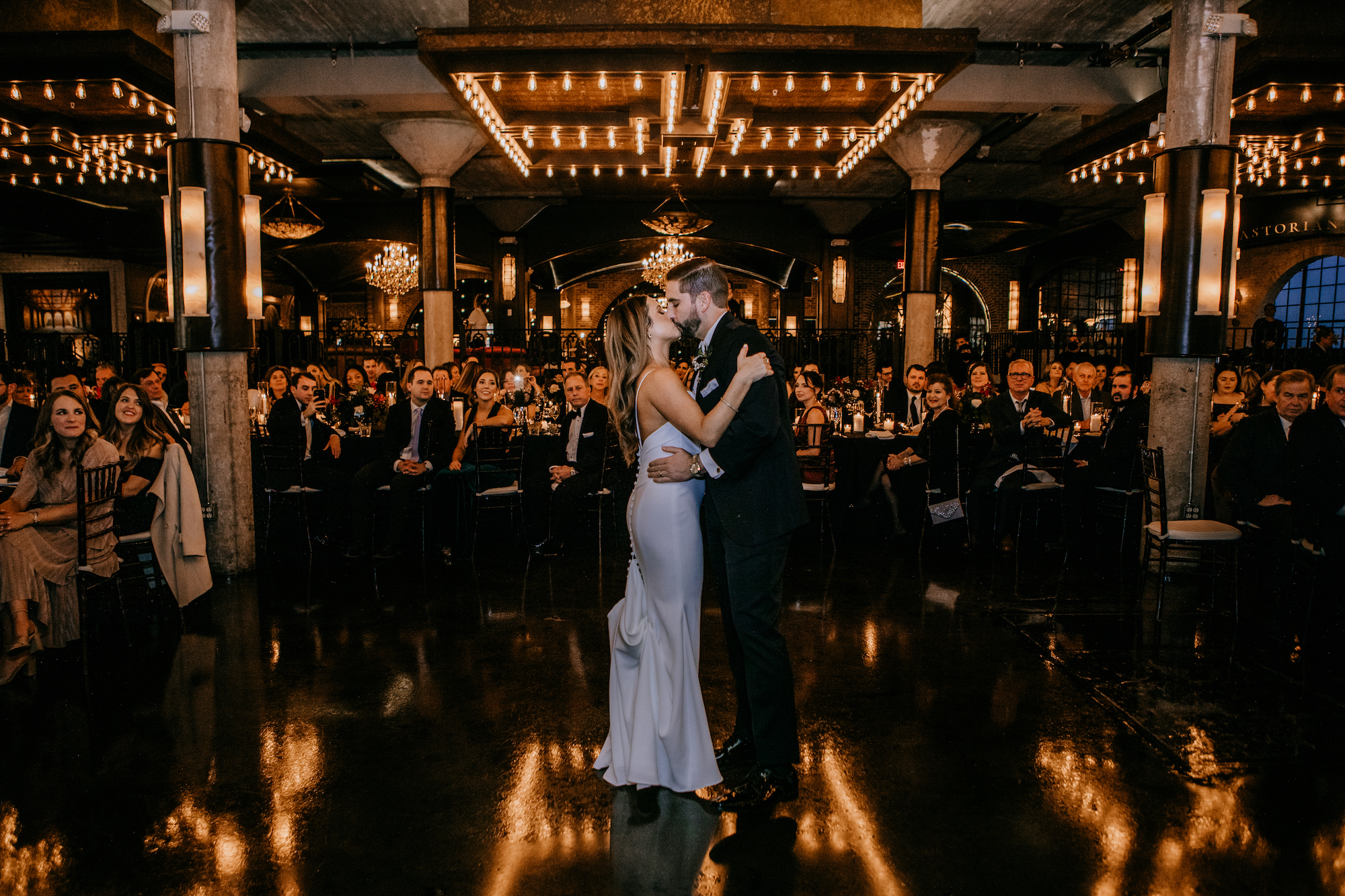 A bride and groom kiss and dance while their wedding guests watch them during their Jewel Toned Wedding With Art Deco Vibes.