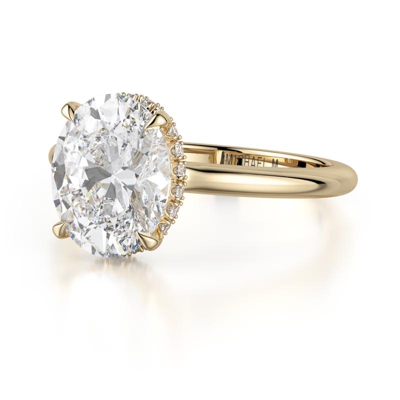 A round diamond engagement ring with a gold band from I W Marks, a jeweler in Houston, TX.
