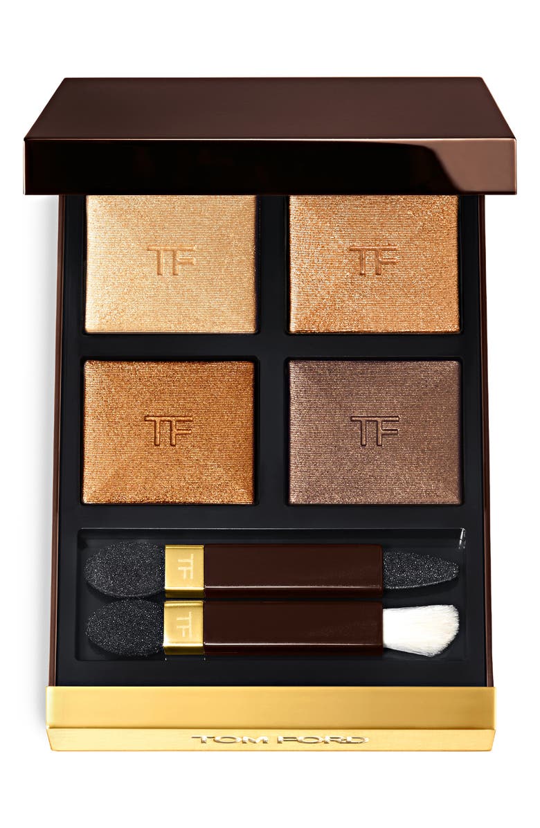 An open Tom Ford eyeshadow palette with two eyeshadow applicators and four shimmering eyeshadows in yellow gold, bronze and brown shades. 