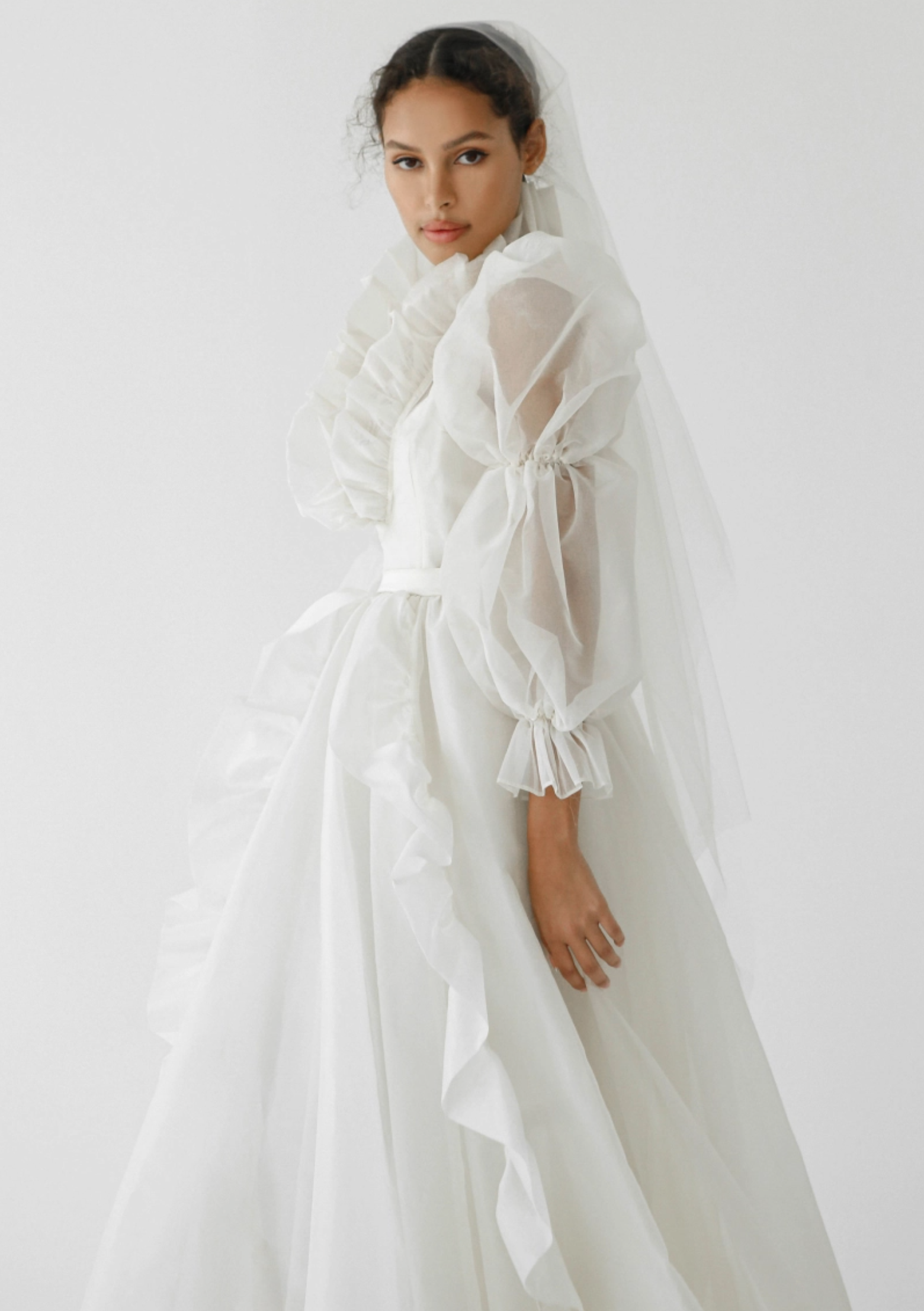A sheer, long-sleeve flowy wedding gown designed by Odylyne the Ceremony for the spring and summer 2023.