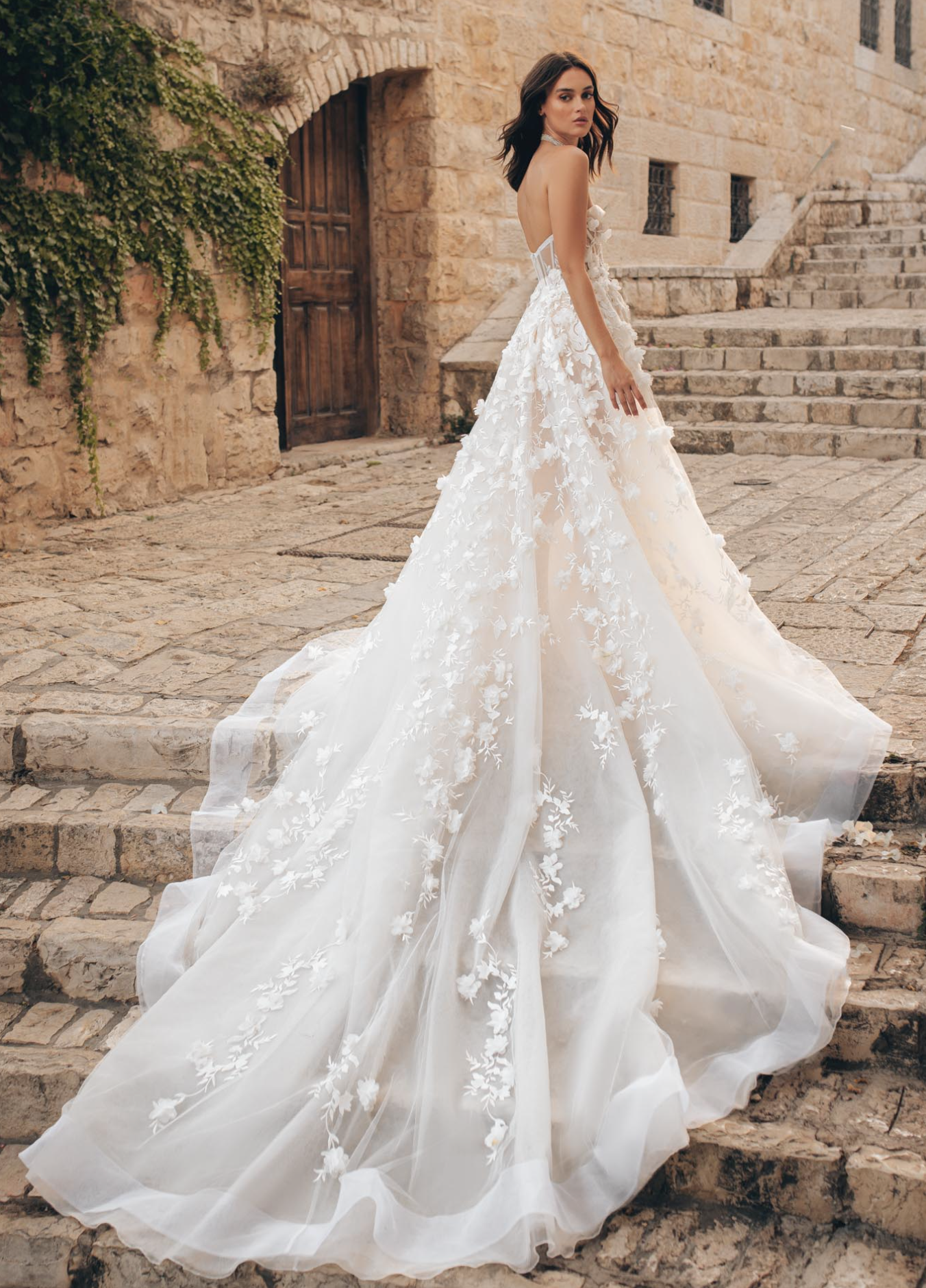 A bride wears a Berta wedding gown that has a flowy skirt with 3D embellished flowers stitched onto it.