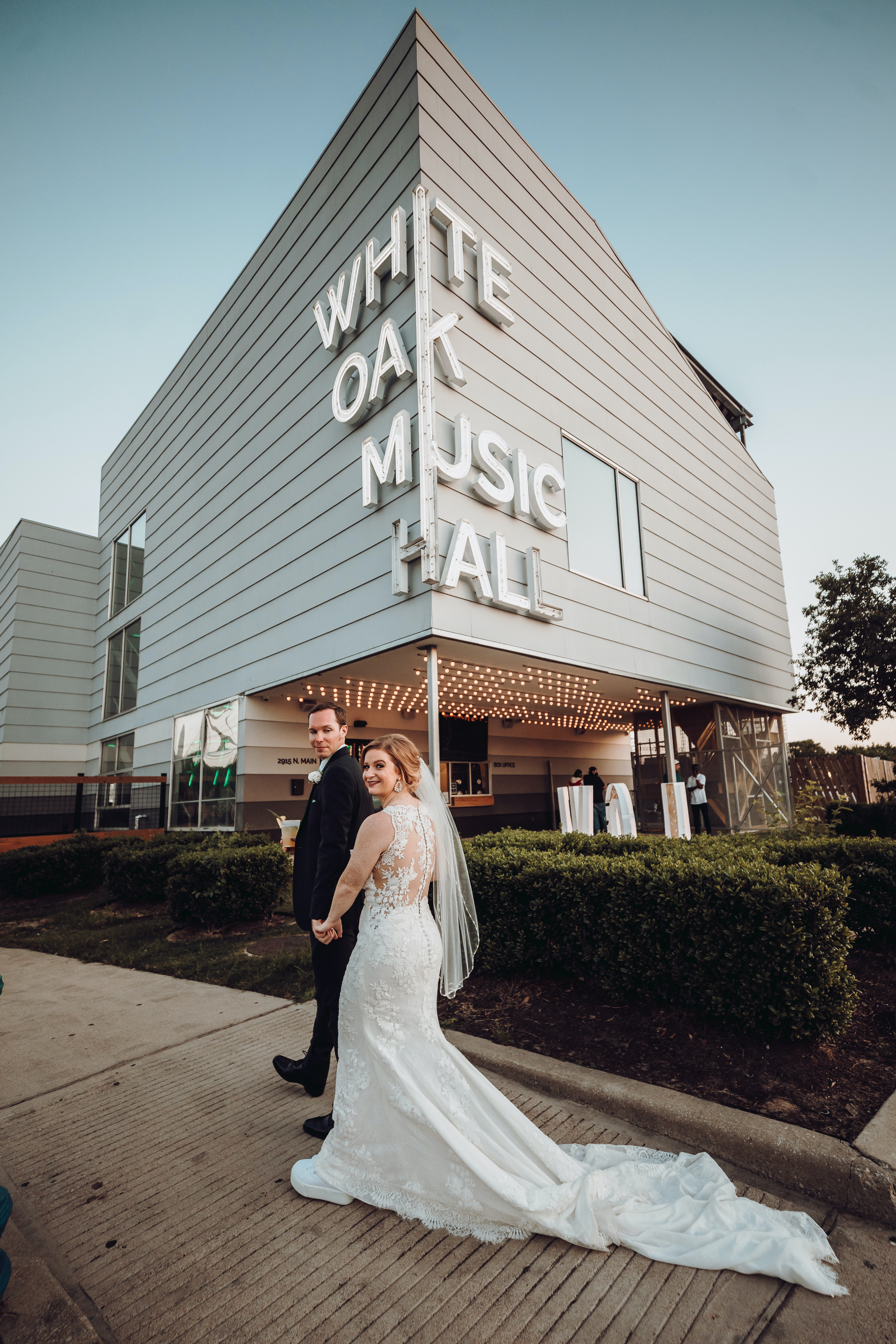 A bride and groom walk in front of their wedding venue in Houston, TX.