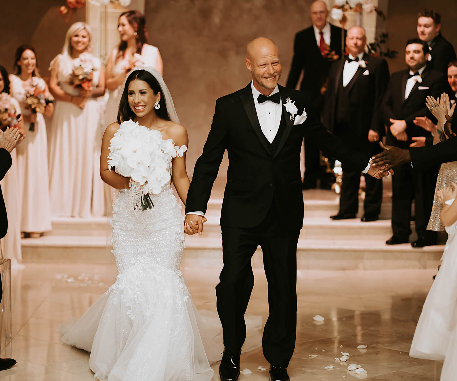 The bride and groom smile and walk down the aisle holding hands after their first kiss as husband and wife. 