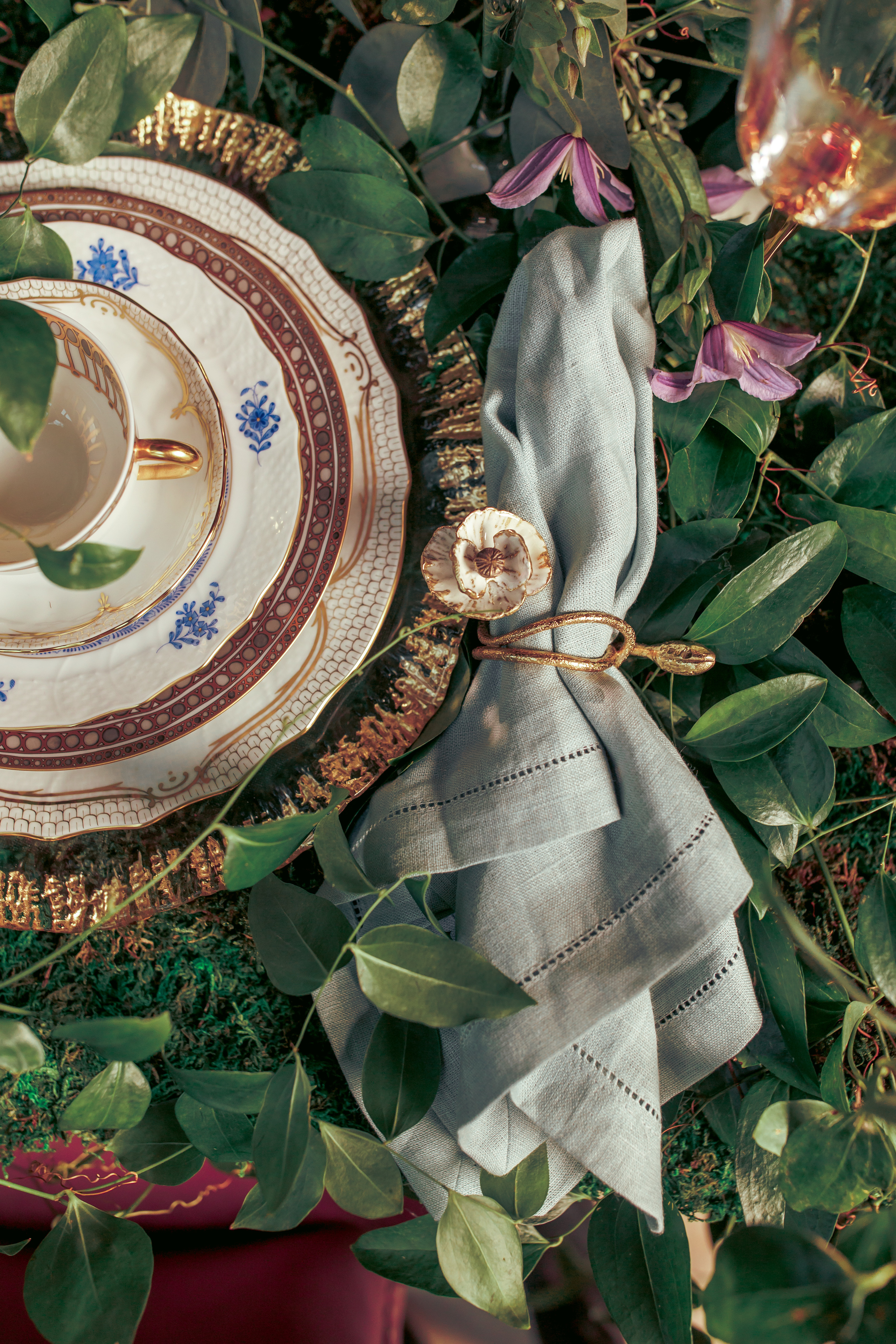 Fine china by Herend and a linen napkin with a floral napkin atop a vine and floral covered table at a styled shoot at The Bell Tower on 34th.