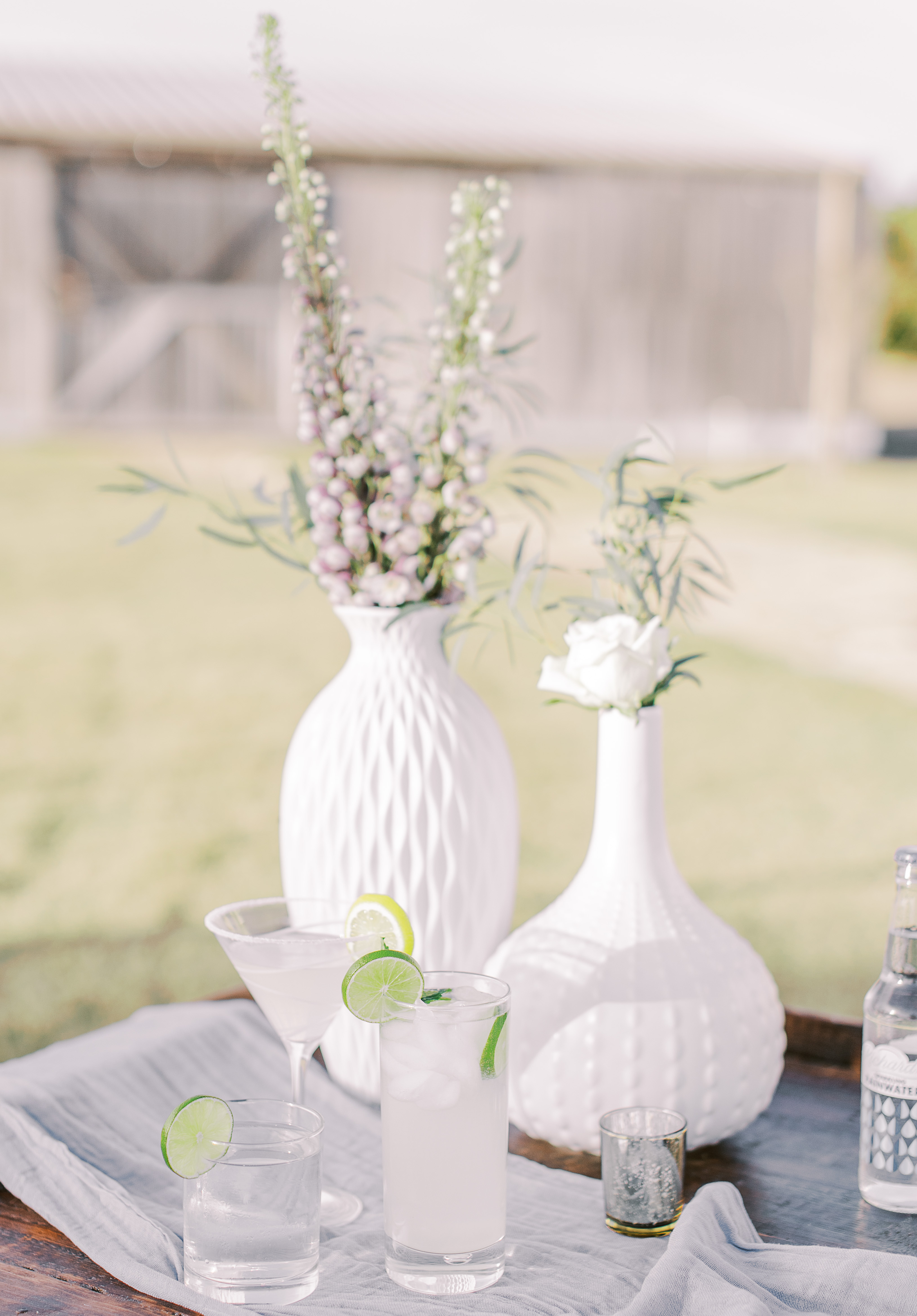 Three cocktails with lemons and limes are set up outside for a sunlit hill country wedding editorial in Dripping Springs, TX.