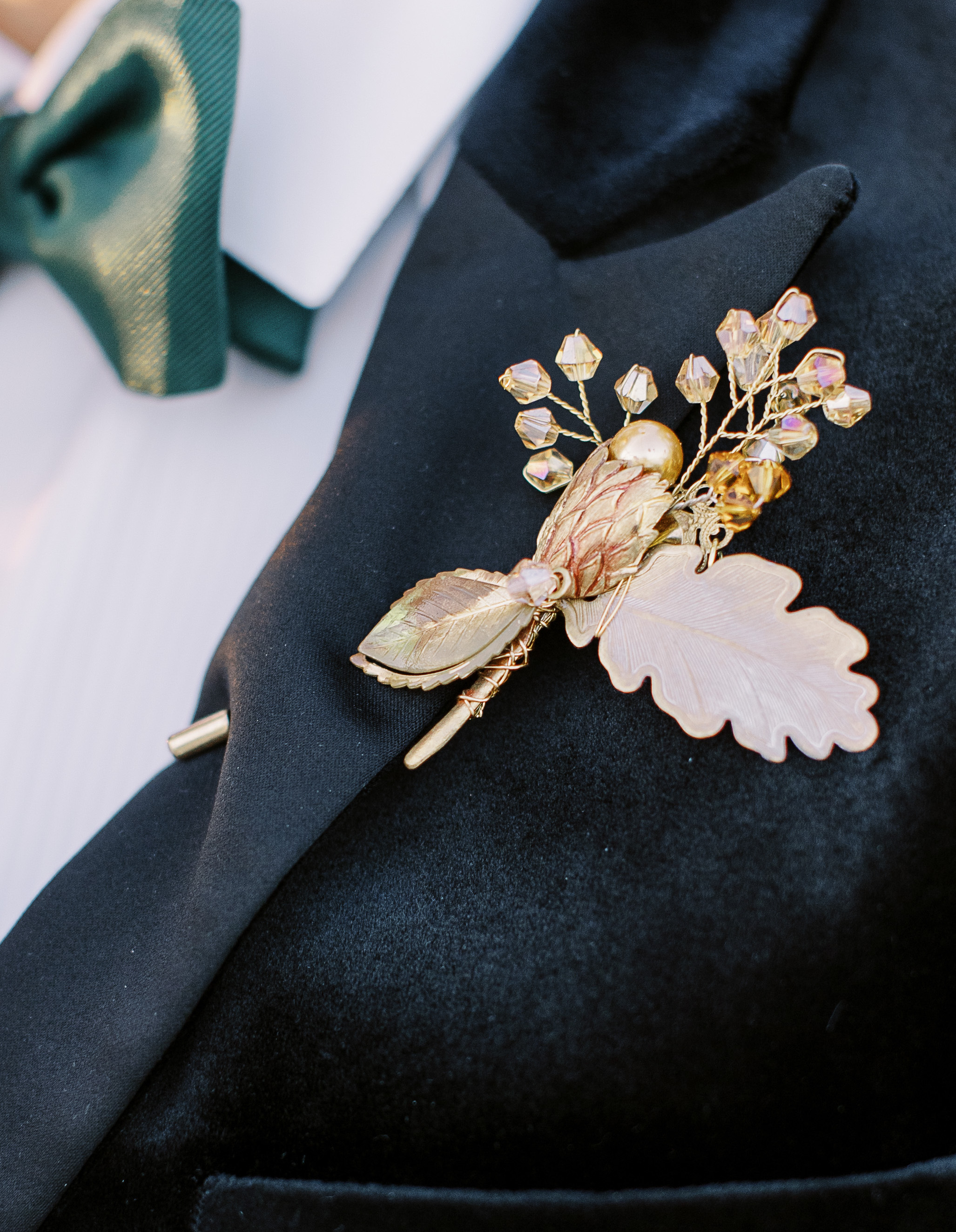 A groom's boutonnière is made of gold metal leaves with crystals imitating the look of flowers. 