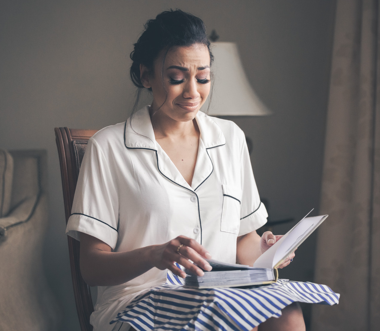 A bride gets emotional looking through a photo album before her wedding ceremony.