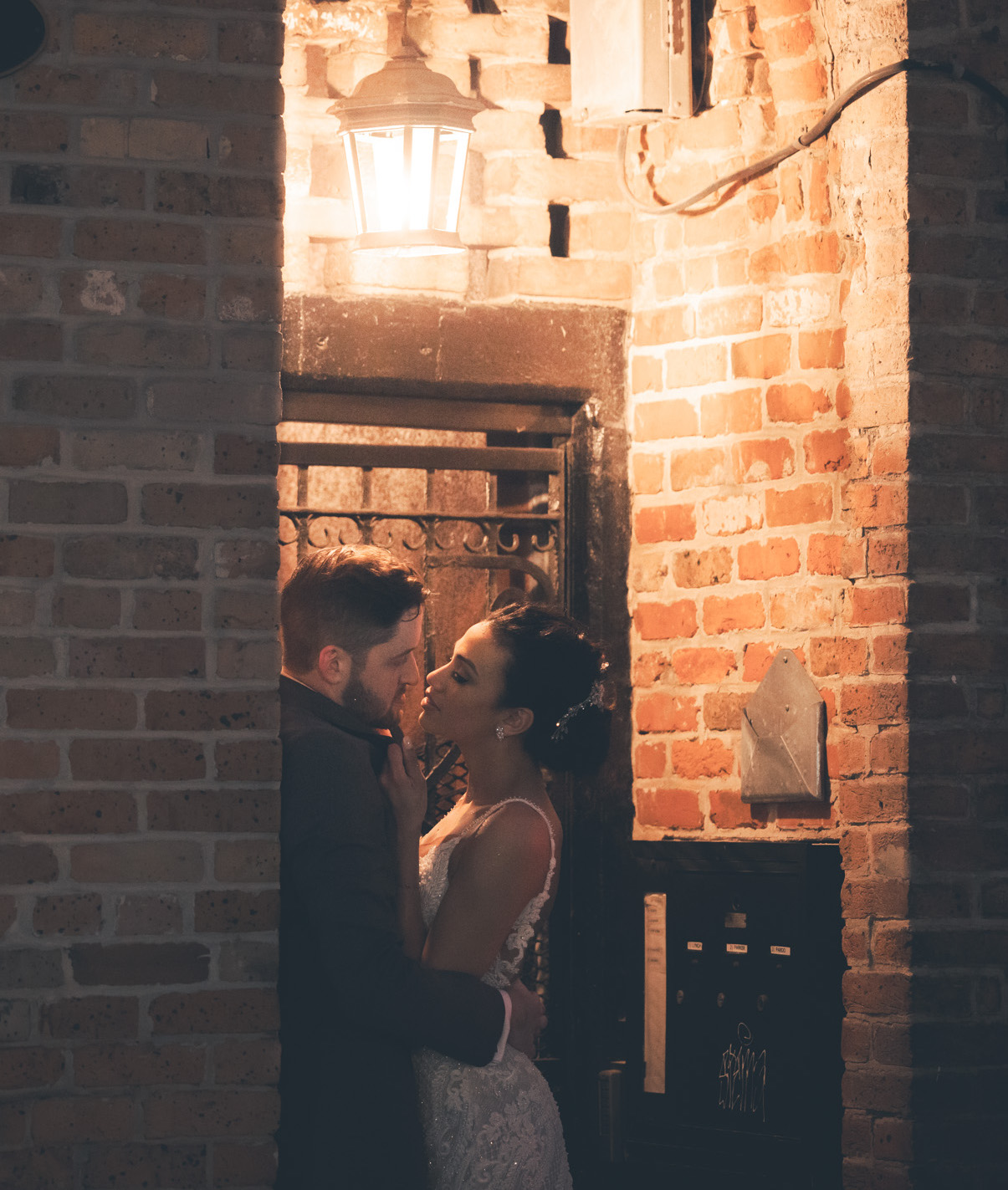 A bride and groom are standing next to a brick wall in New Orleans.