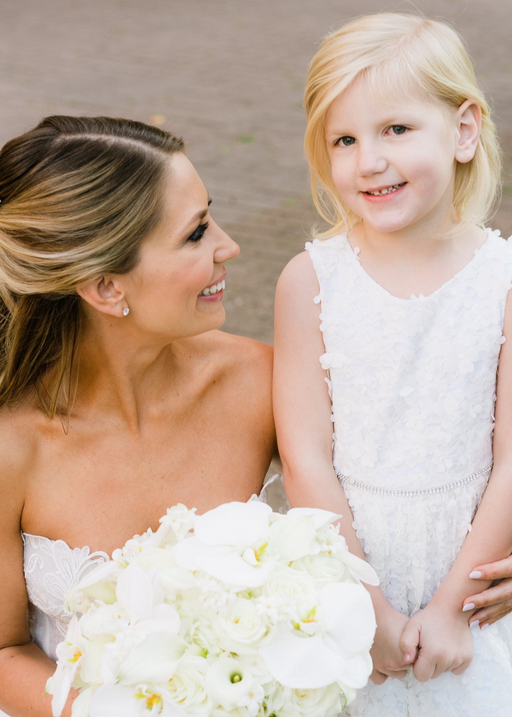 A bride kneels next to her flower girl before her wedding in Houston, TX.