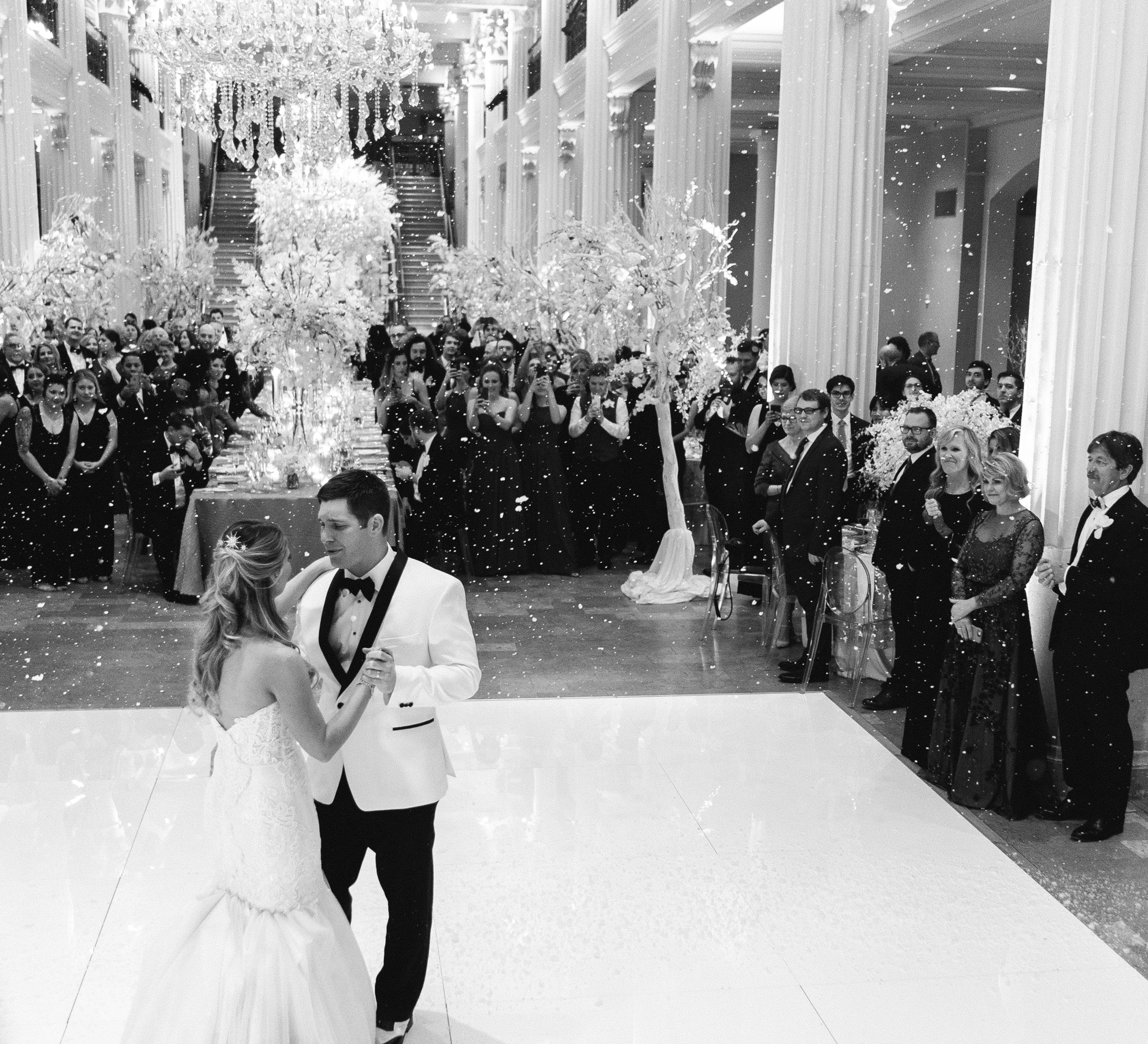 A black and white photo of a bride and groom dance on the dancefloor at their winter wedding at Corinthian Houston.