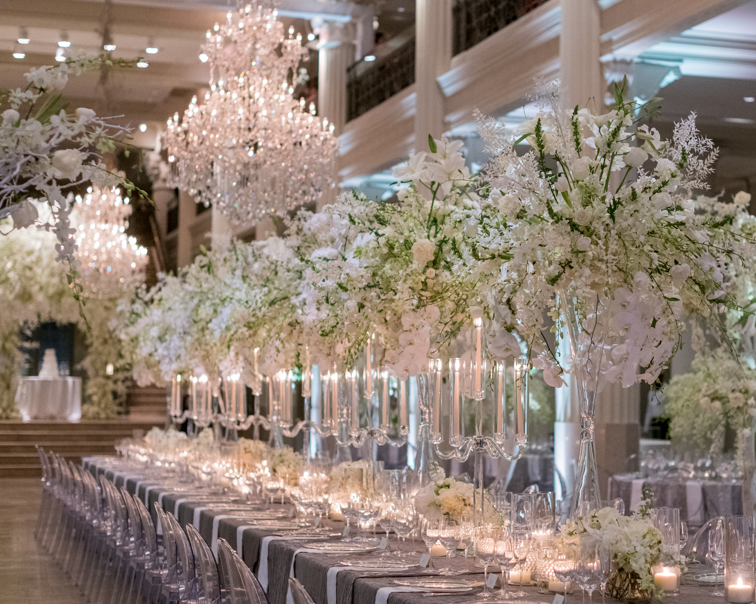A family style reception dinner is set up with tall white flower centerpieces for a wedding in Houston.