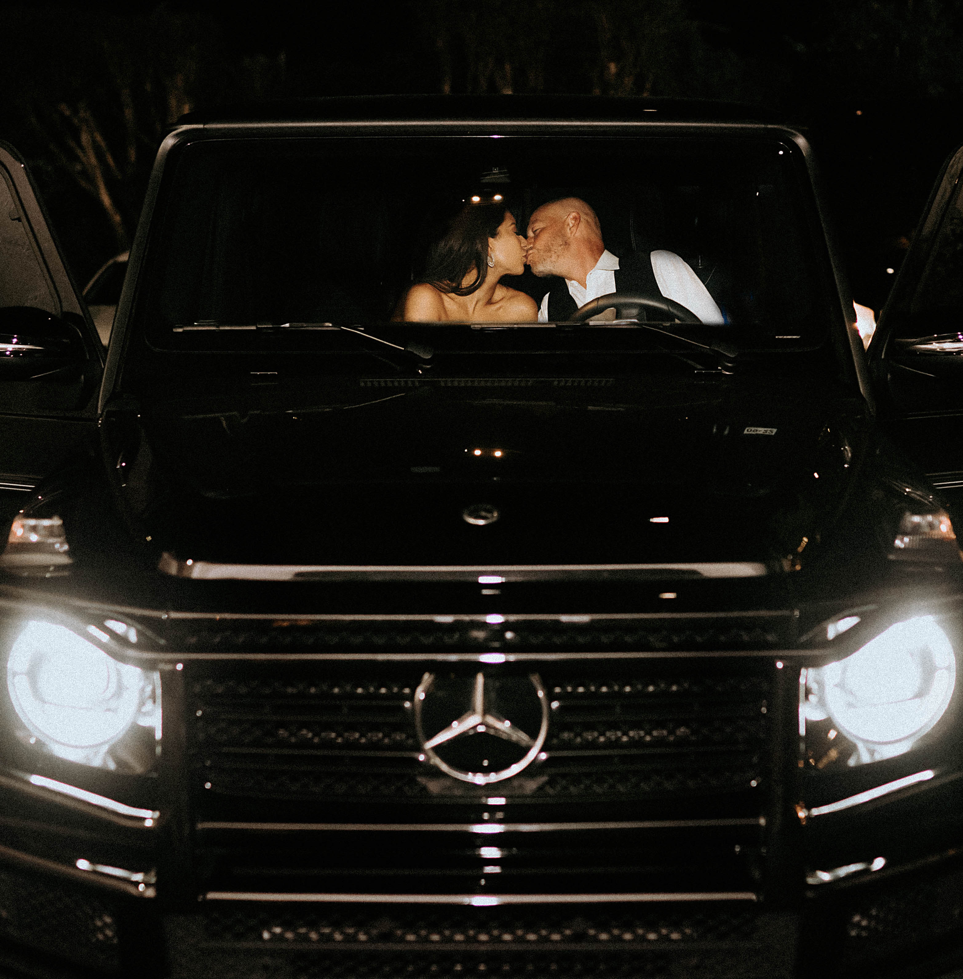 A bride and groom kiss in a black Mercedes G-Wagon after their earth-toned wedding at The Bell Tower on 34th in Houston, TX.