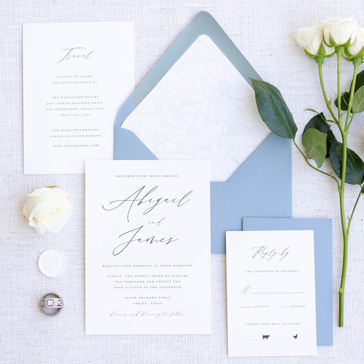 White and blue invitation suite with cursive font. 