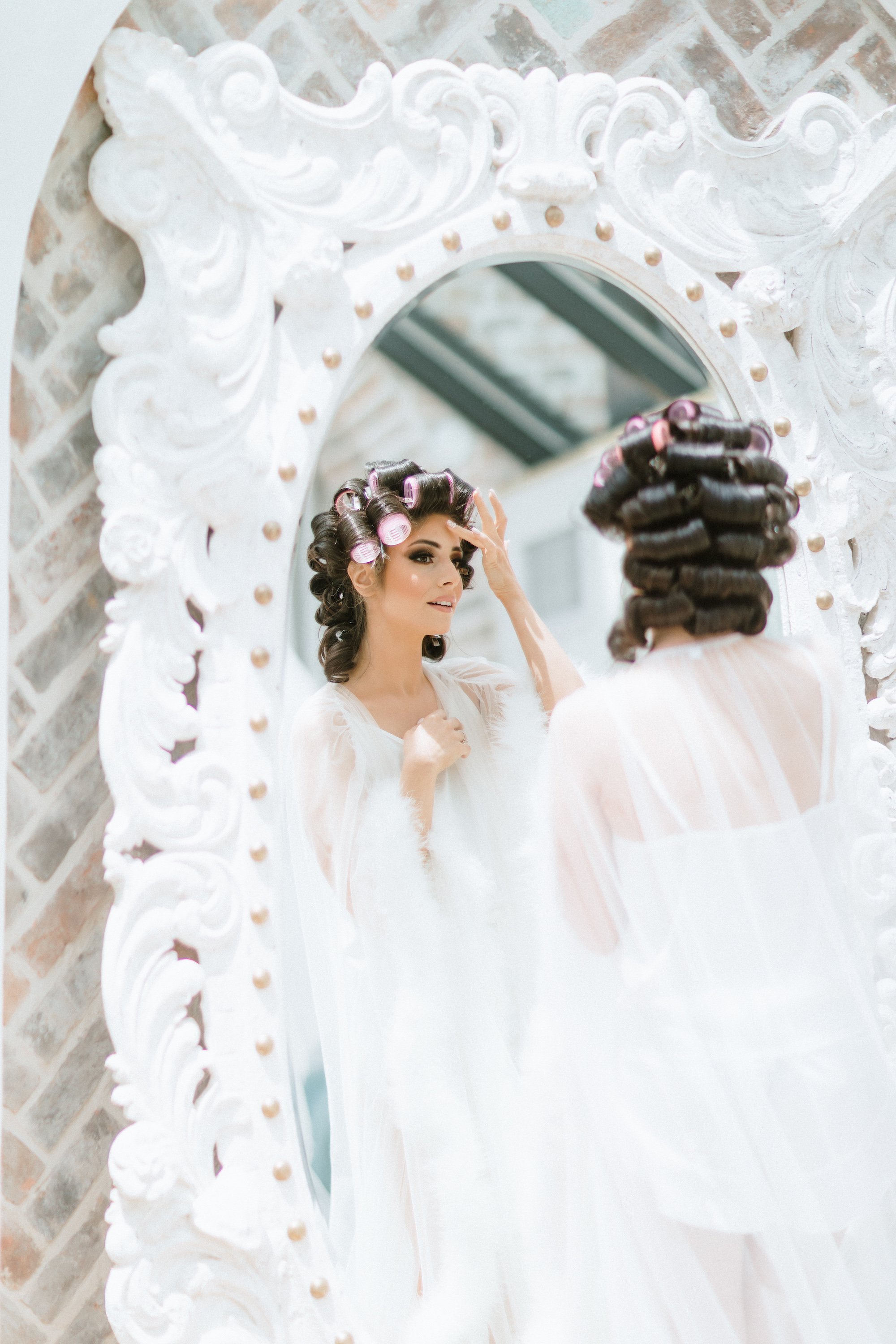 A bride looks in the mirror as she is getting ready for her pink and lilac Persian wedding in Montgomery, TX.