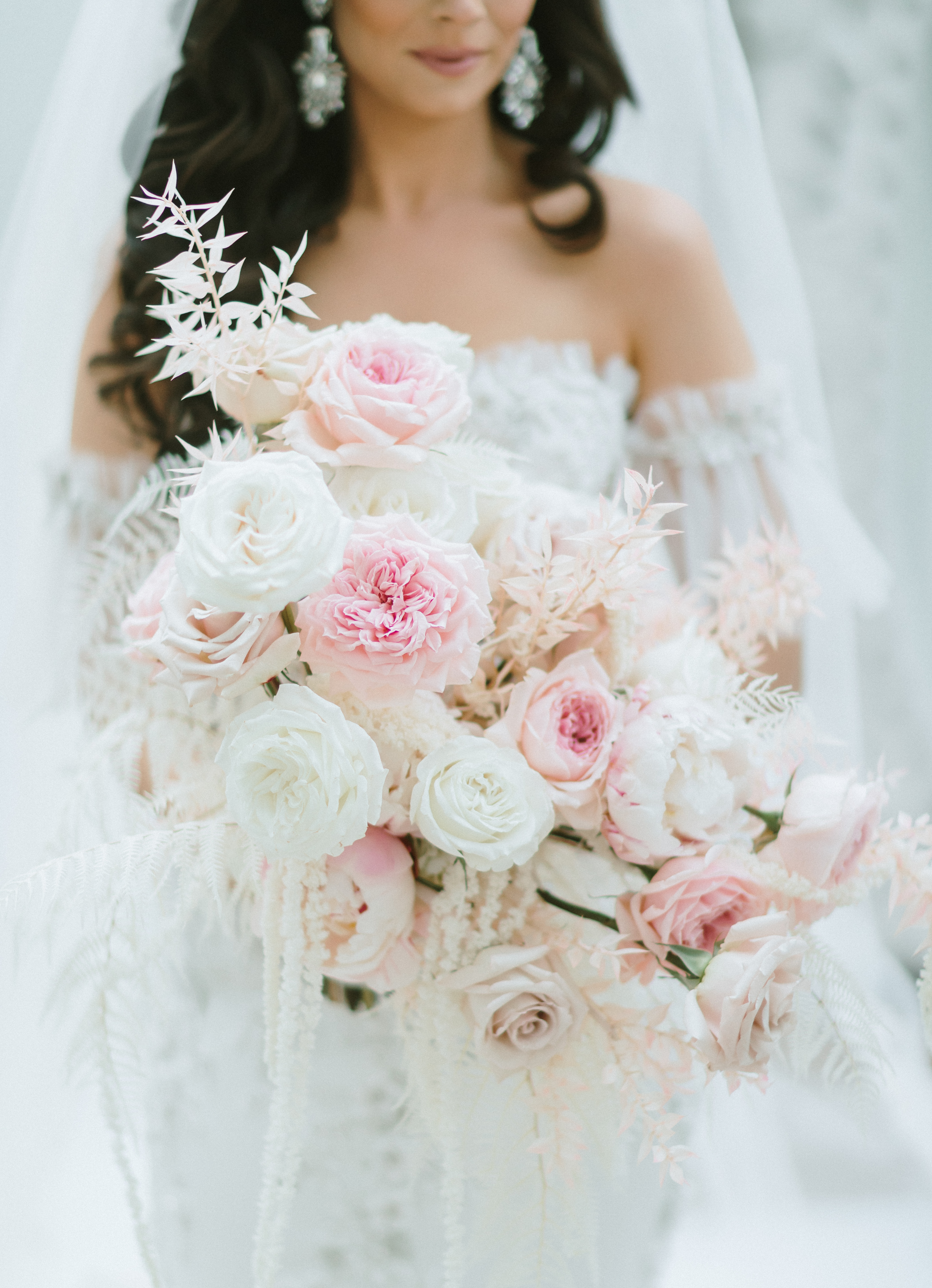 A bride holds her bridal bouquet with white a blush pink flowers for her wedding in Montgomery, TX.