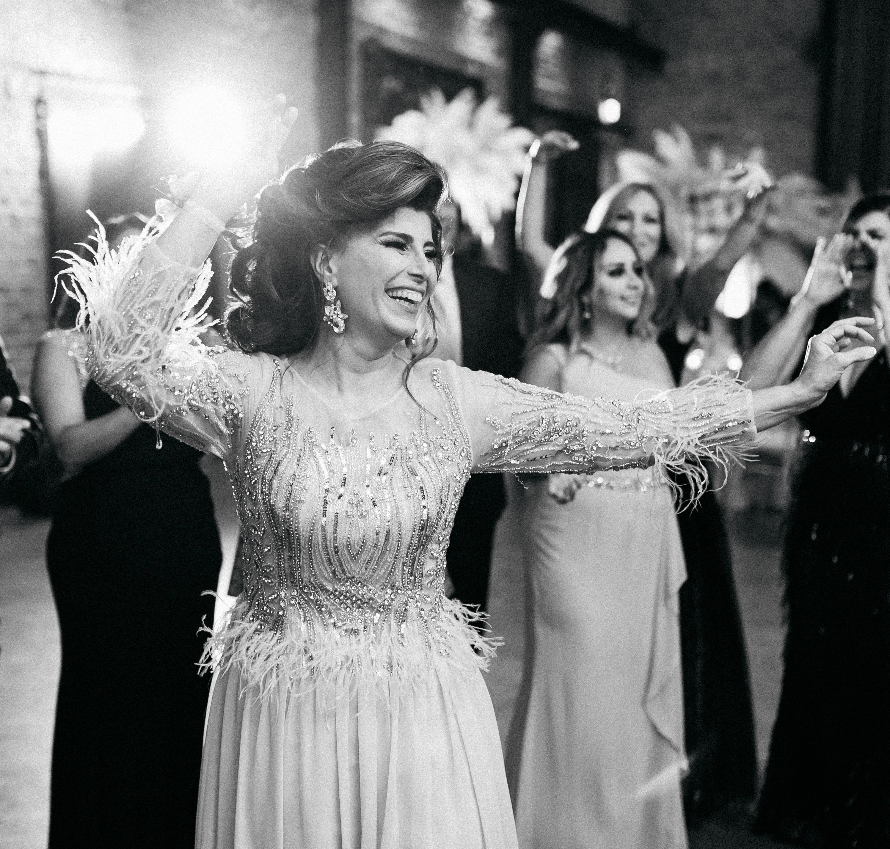 The bride's mother is smiling and dancing with the crowd during the pink and lilac Persian wedding.