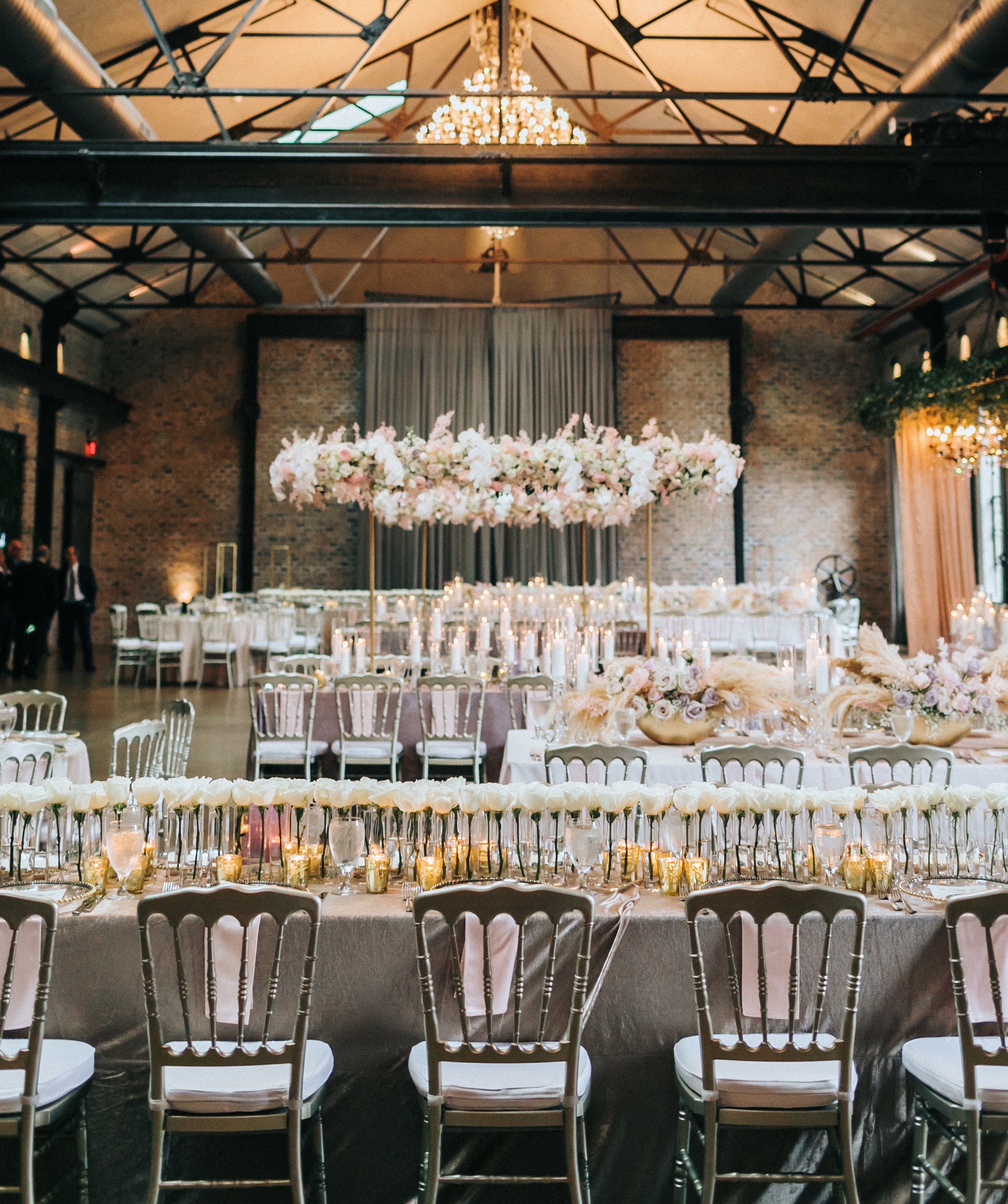 A wedding reception is decorated with white, pink and lilac flowers and decor.