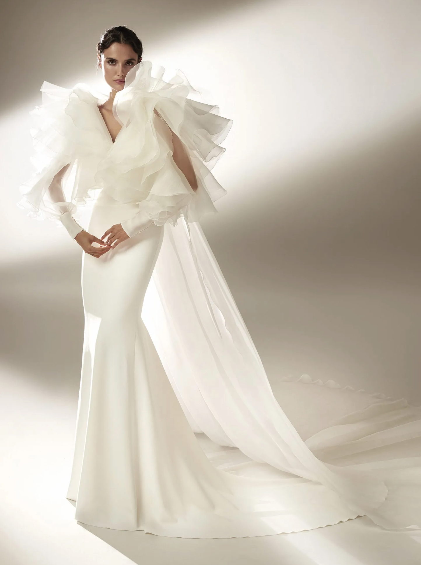 A bride wears a ruffle sleeve dress that is fitted and flares at the bottom. Pronovias.