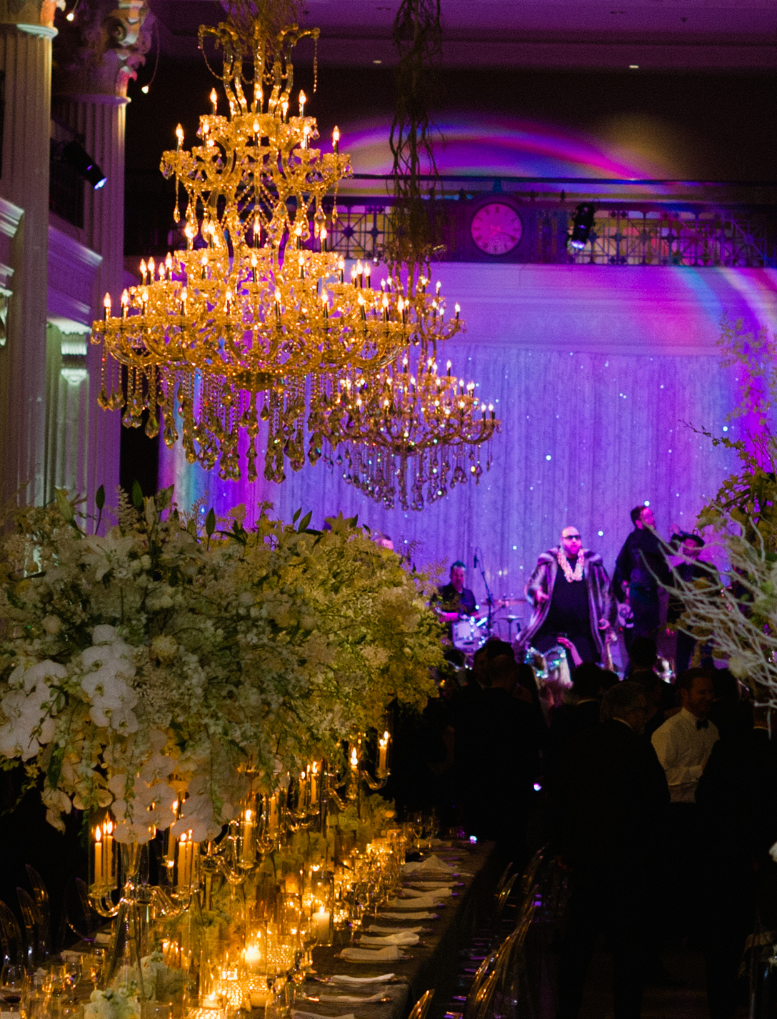 A reception room has a live band performing for a winter wedding in Houston. The room is dimly lit with a purple light shining on stage.