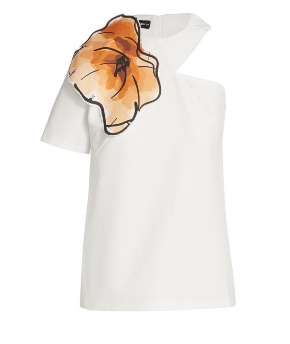 A white off-the-shoulder blouse with a big orange flower on one sleeve. Available at Saks Fifth Avenue.