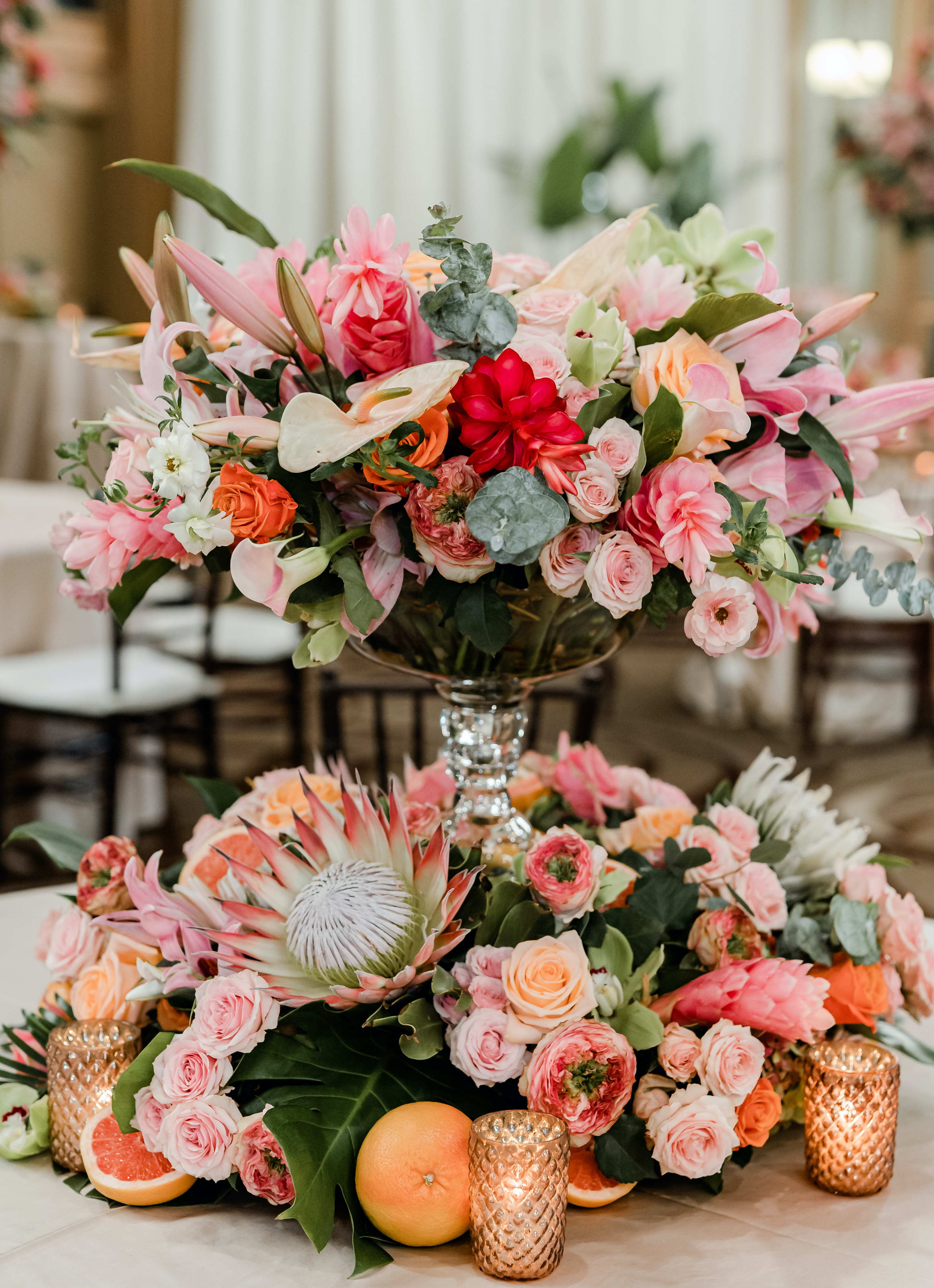 A centerpiece full of bright pink, orange and red tropical flowers sits on a table for a wedding reception at The San Luis Resort, Spa & Conference Center in Galveston, TX.