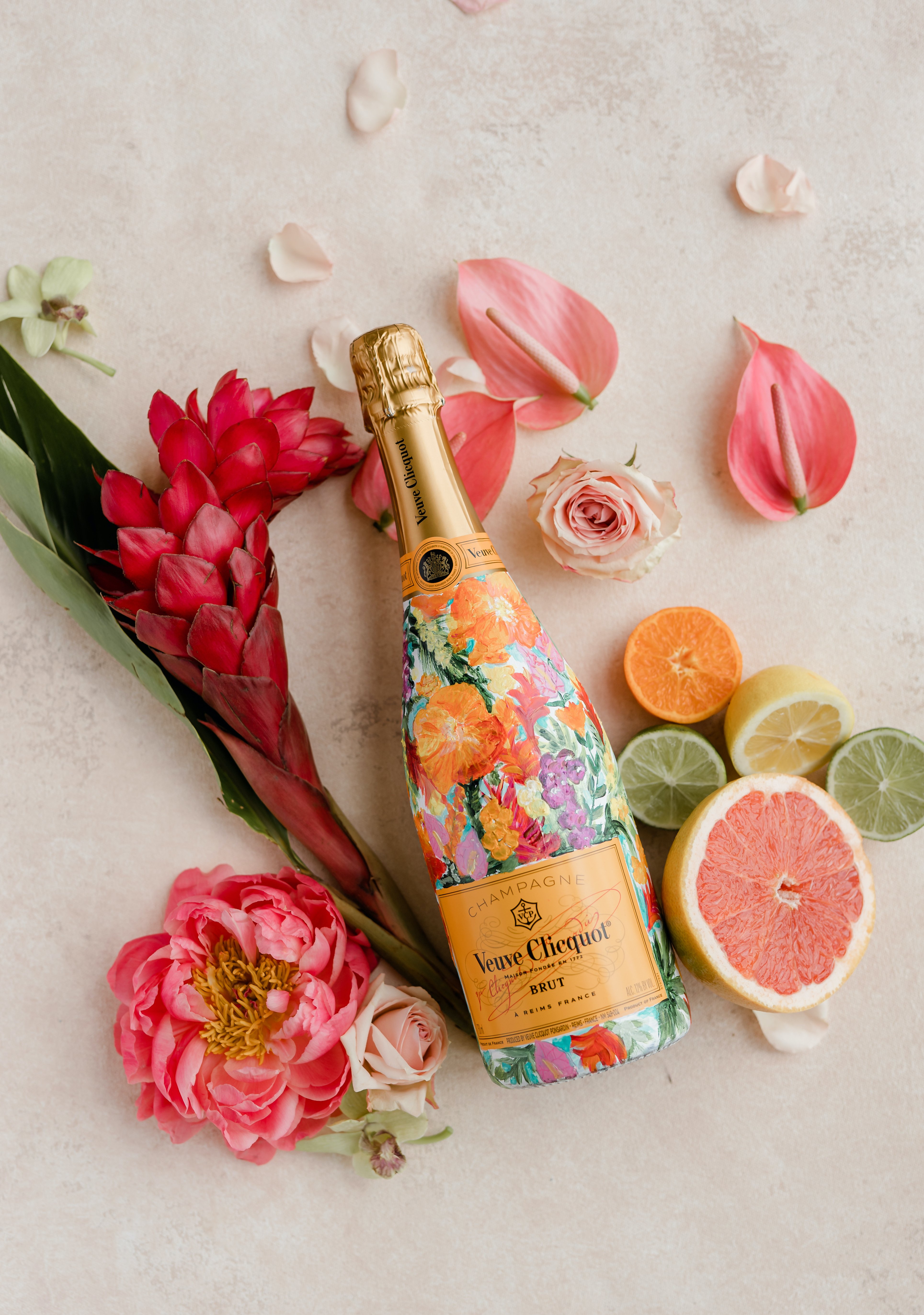 A handpainted champagne bottle is surrounded by citrus and tropical flowers.