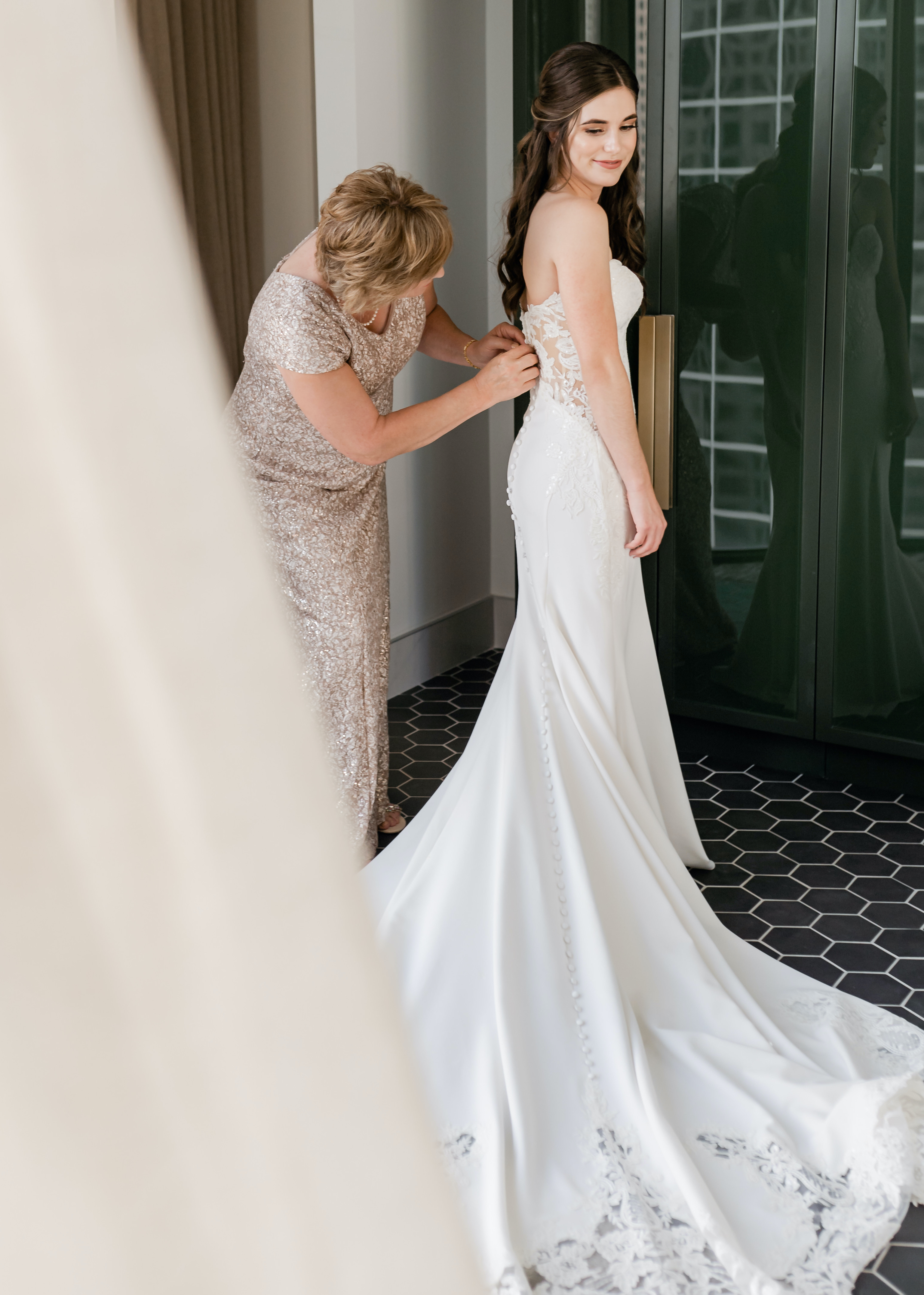 A bride's mother helps her put on her wedding dress before her wedding in Houston, TX.
