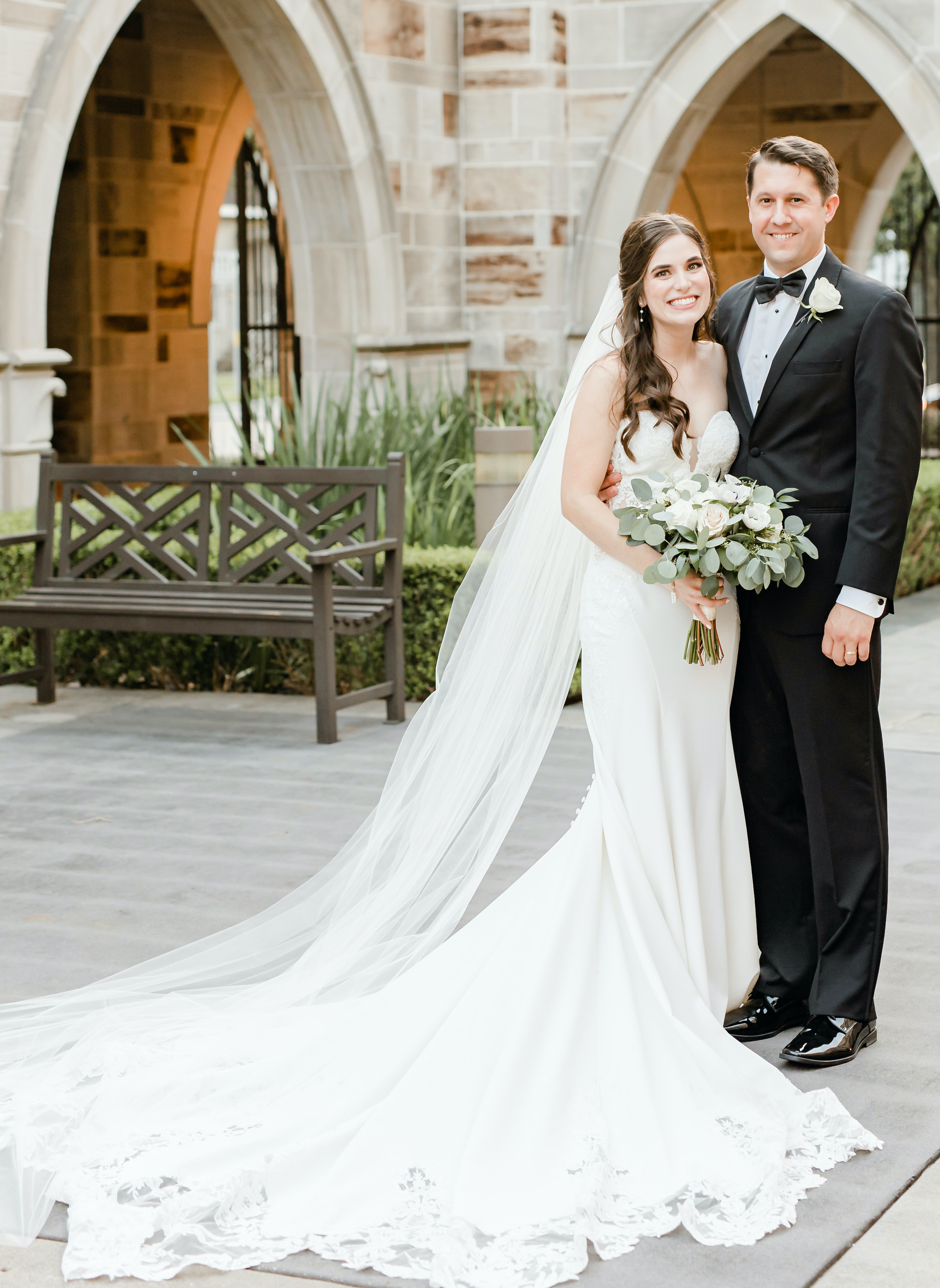 A bride and groom stand next to each other and smile before their wedding reception in Houston.