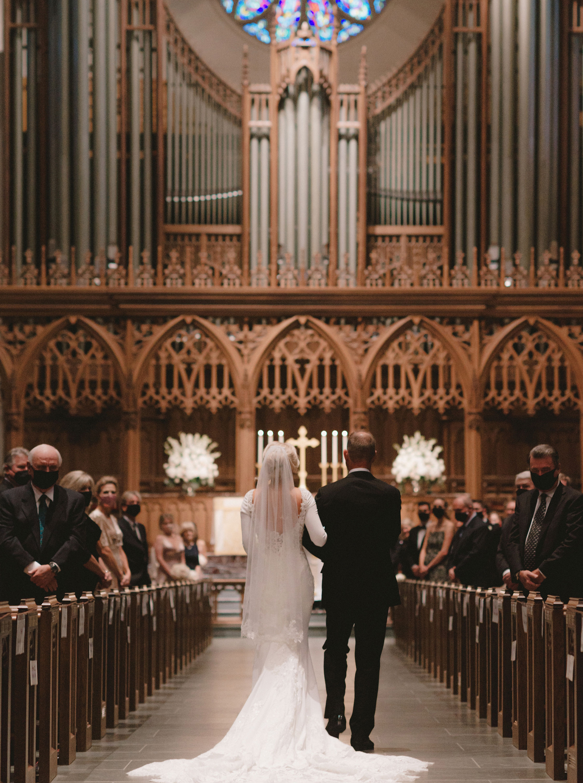 A bride walks down the aisle of a cathedral in Houston with her father.