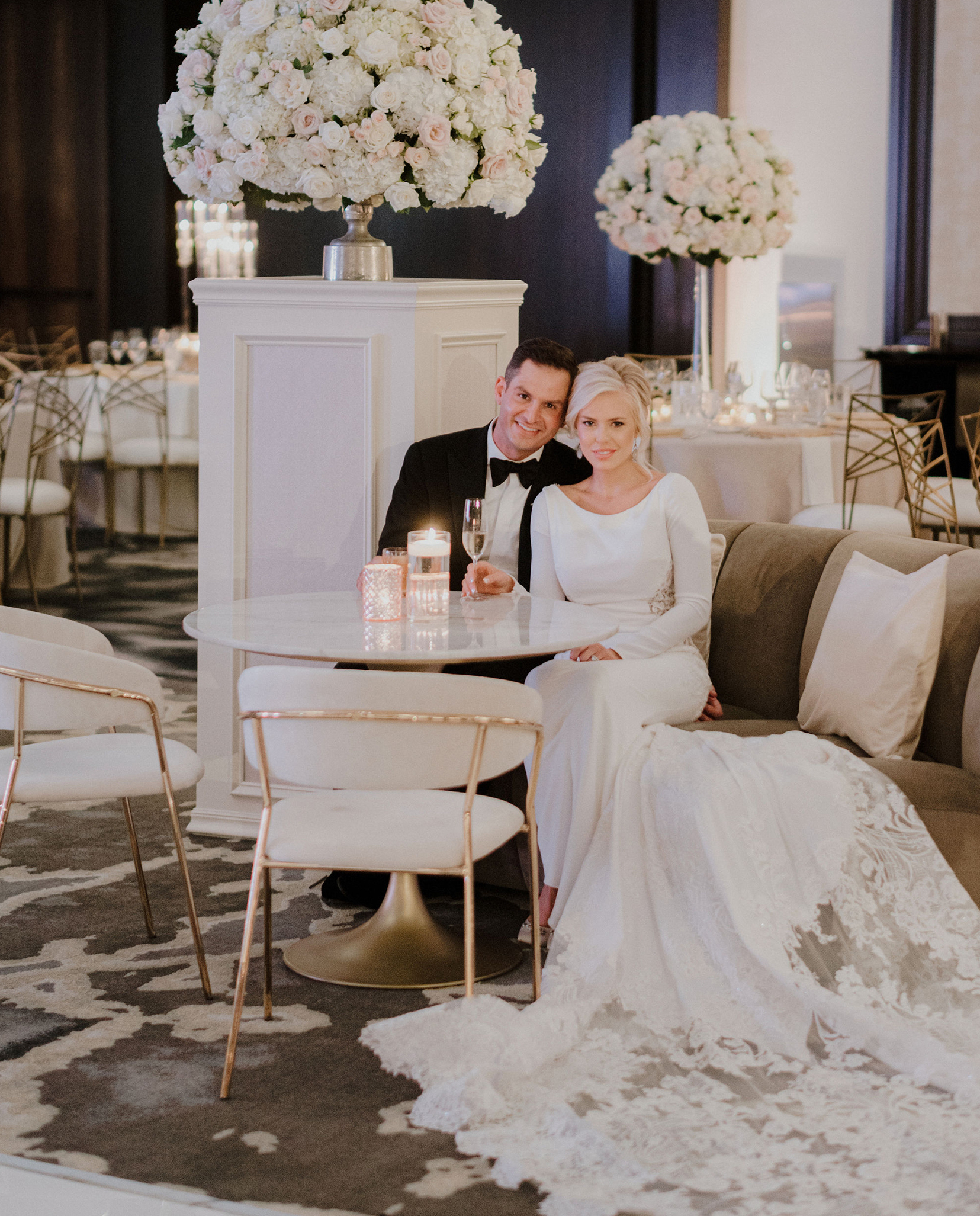 A bride and groom sit in a decorated reception room for their romantic ballroom wedding in Houston.