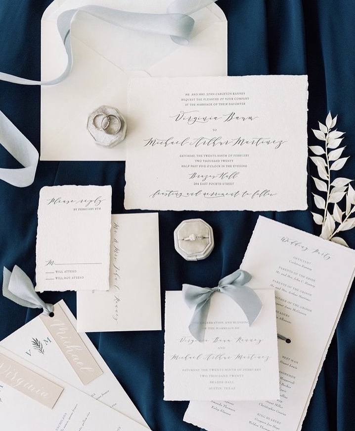 A white and navy blue invitation suite for a wedding.