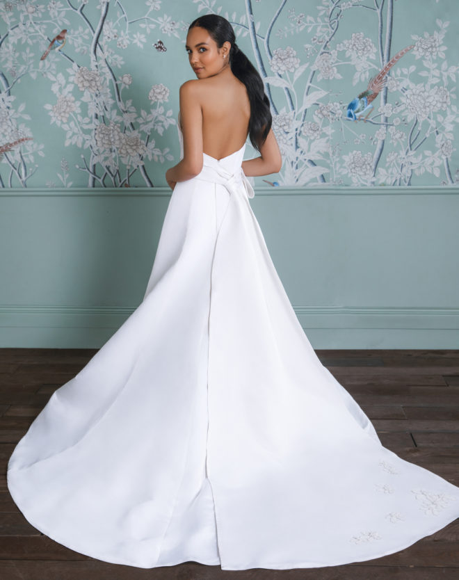 Model in a long white ballgown-style wedding dress with train.