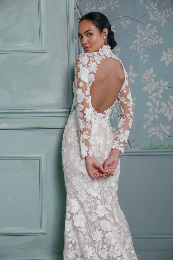 Woman wearing a floral lace wedding gown with an open back by Anne Barge. 