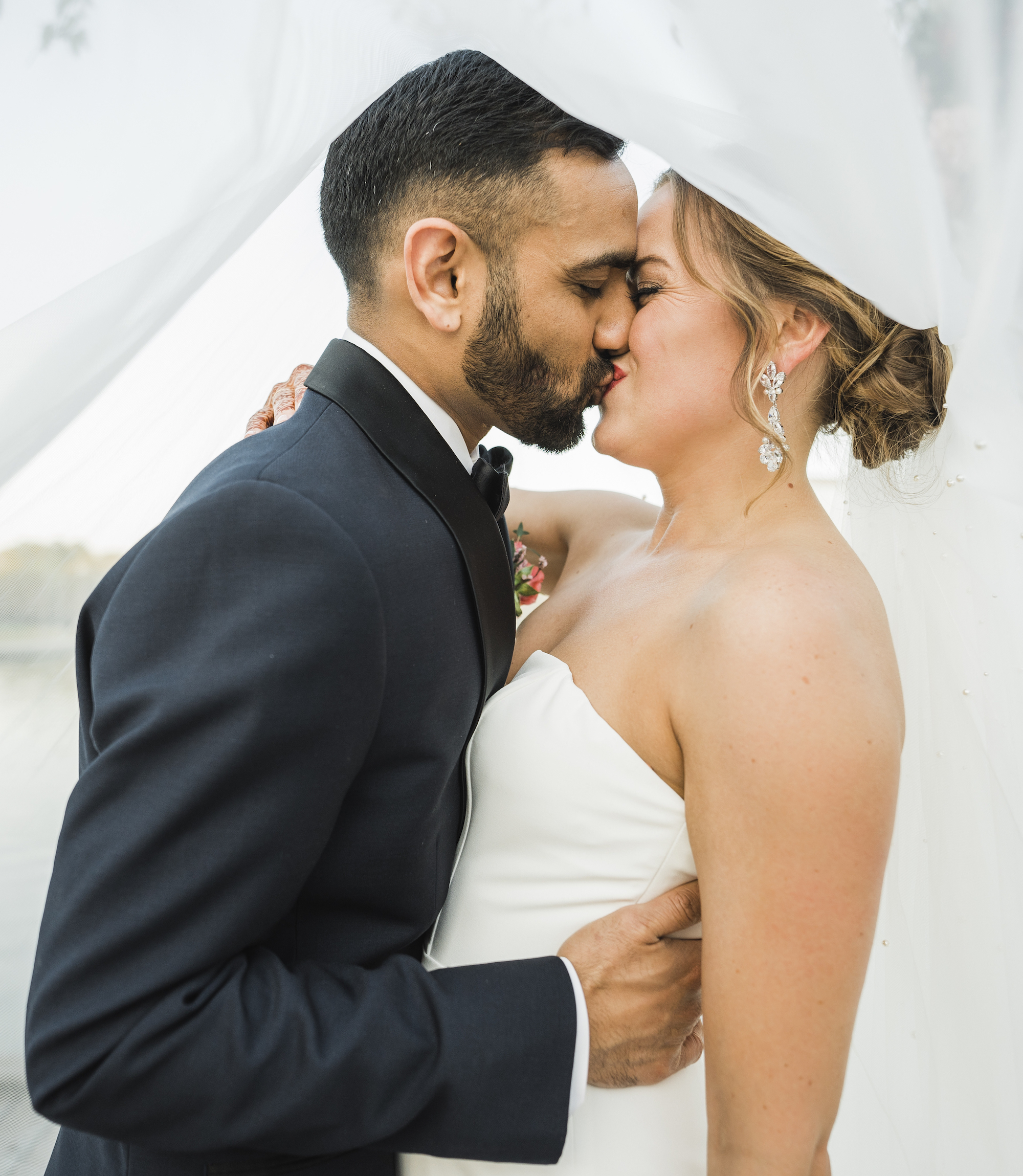 The bride and groom share a kiss under the bride's veil. 